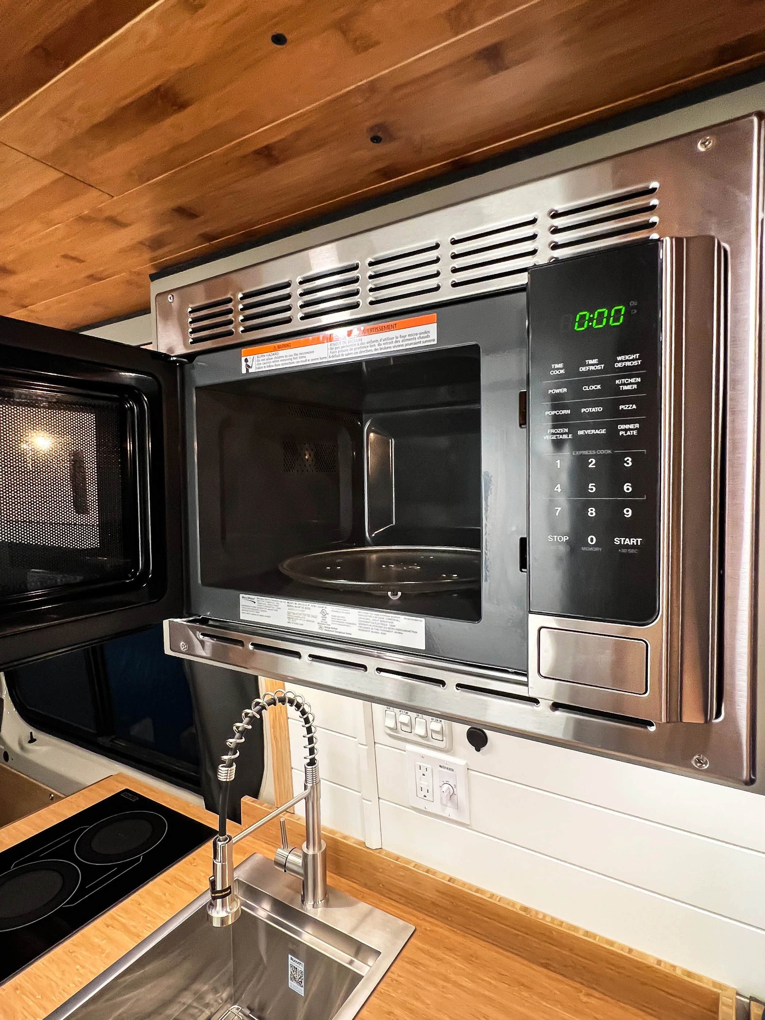 This campervan features a microwave nestled in between the overhead cabinets!