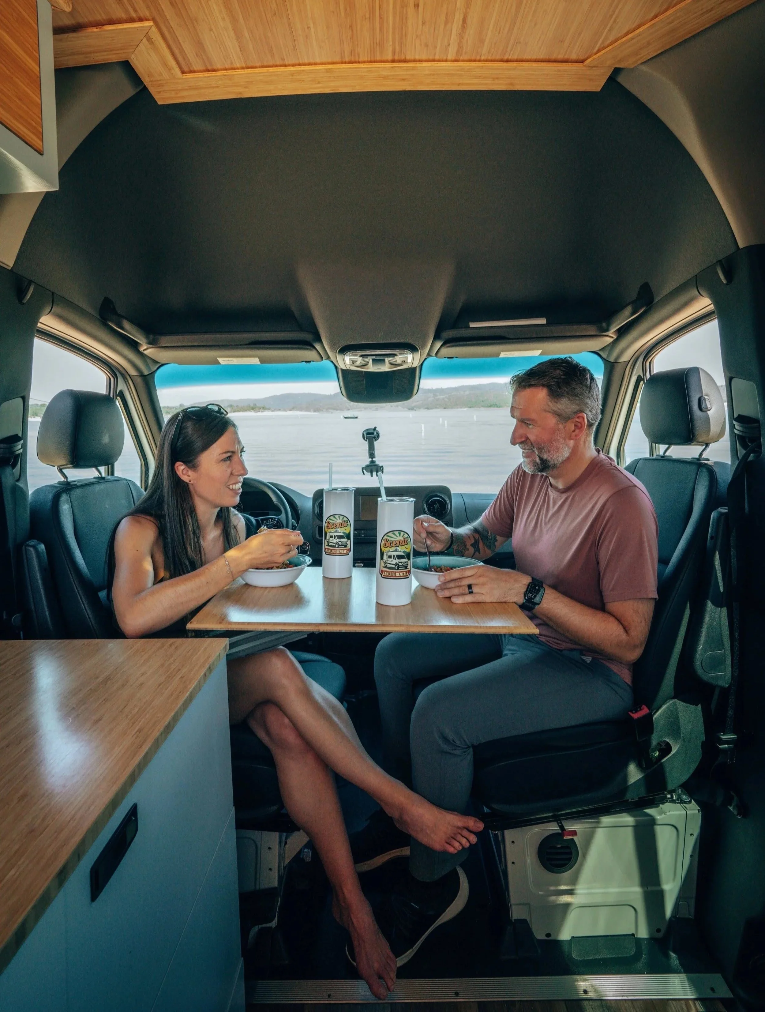 Two people using the swivel seats and eating at Lagun swivel table in campervan