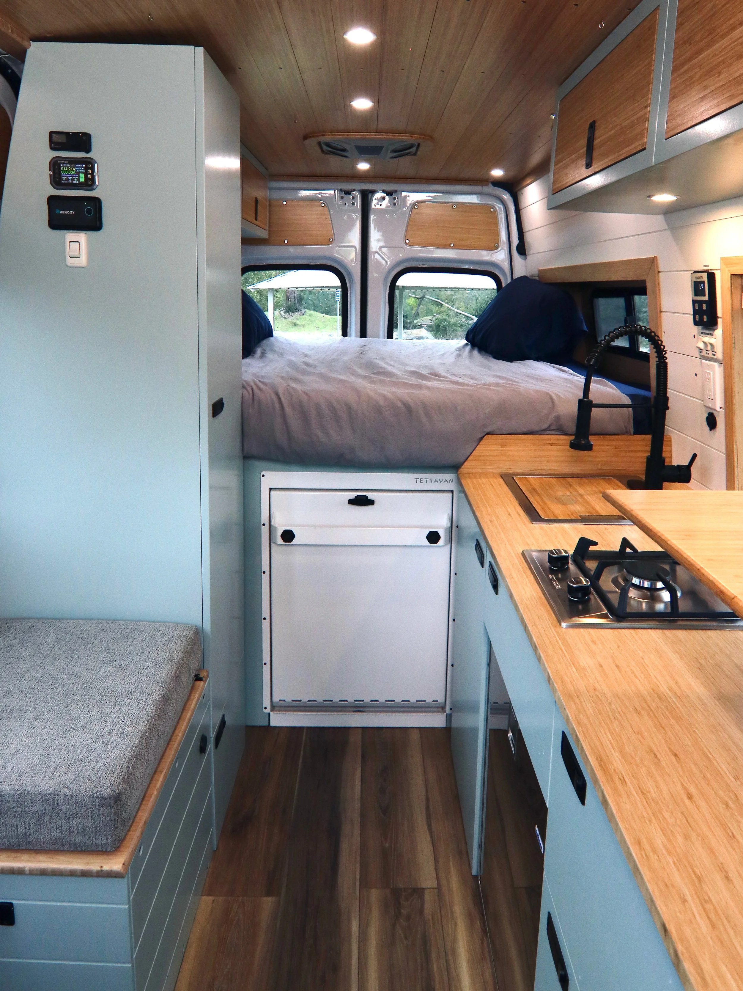 Inside The Aspen Campervan Rental - Driver side has a galley kitchen with Propane stovetop, deep sink, and fridge/freezer. Passenger Side has Bench with toilet and a closet.