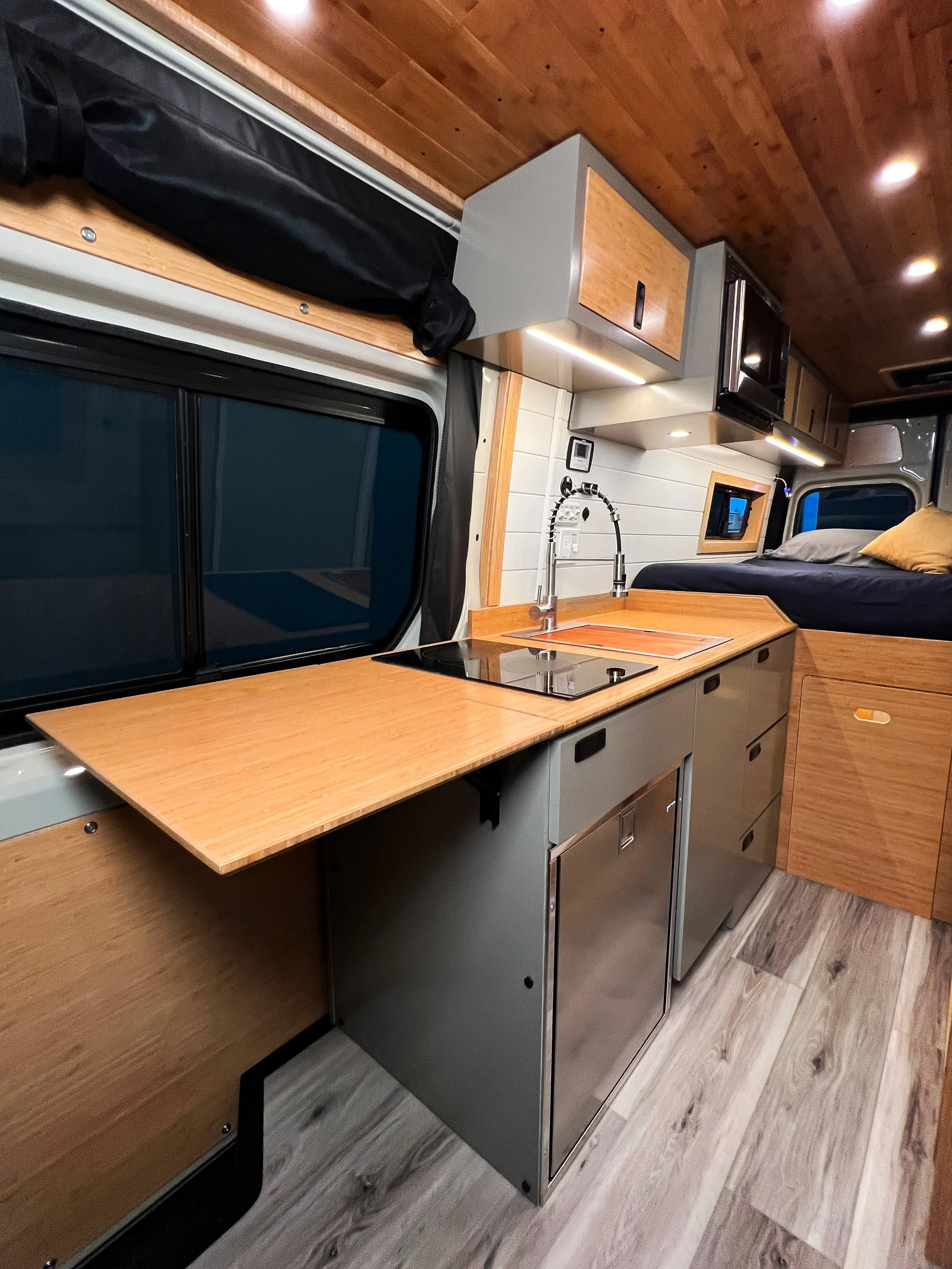 The flip up table provides plenty of countertop space for cooking in the Cascade rental campervan, plus storage for your supplies in the overhead cabinets and galley drawers