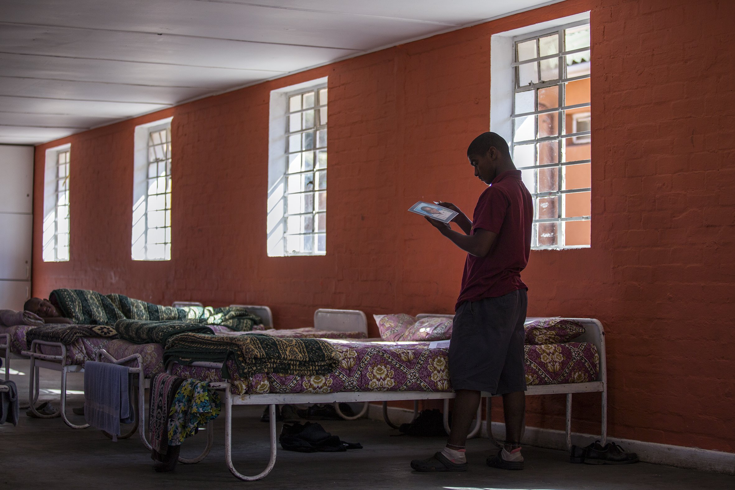 A student looks at a family photograph in one of the dormitories at the Ottery Youth Care Centre. April 2017.