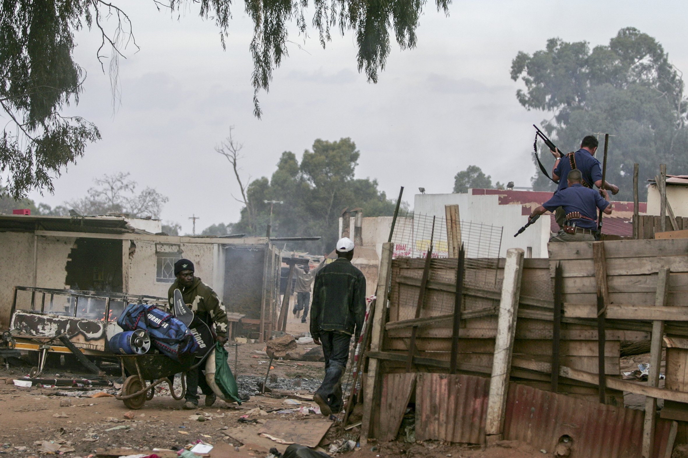A policeman trains his shotgun on a man during violent clashes between the police, foreigners and local residents. Makausi, east of Johannesburg, South Africa.