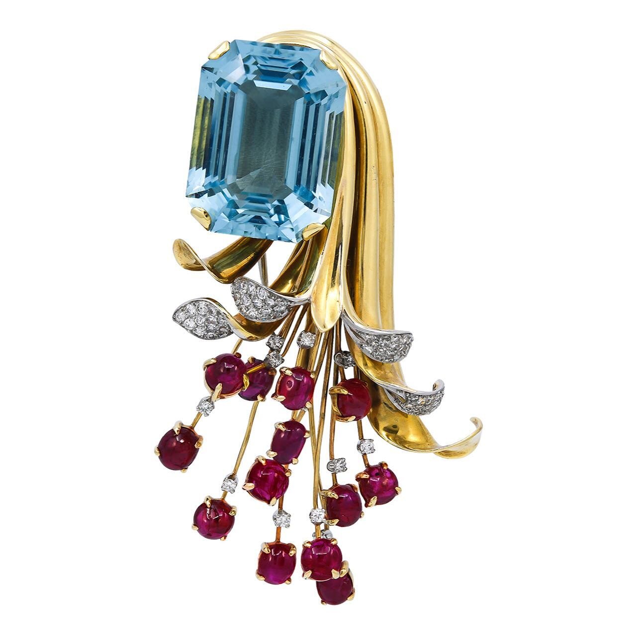 Abstracted gold floral brooch set with a large rectangular-cut aquamarine, extending into a wirework spray set with cabochon rubies emerging from diamond-set petals. Paul Flato, ca. 1940. Available✨