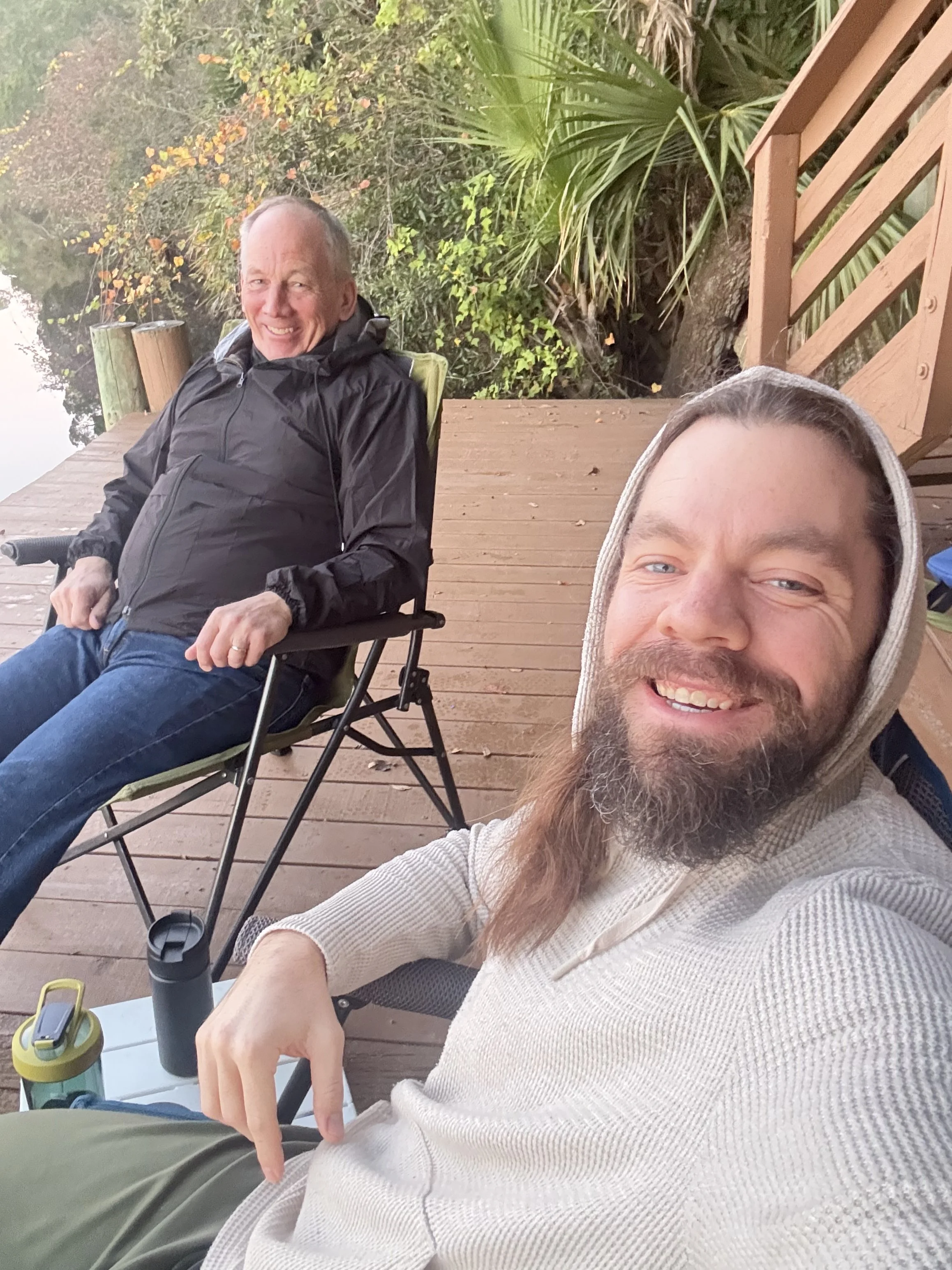 Father and son enjoying early morning sunrise over the river.