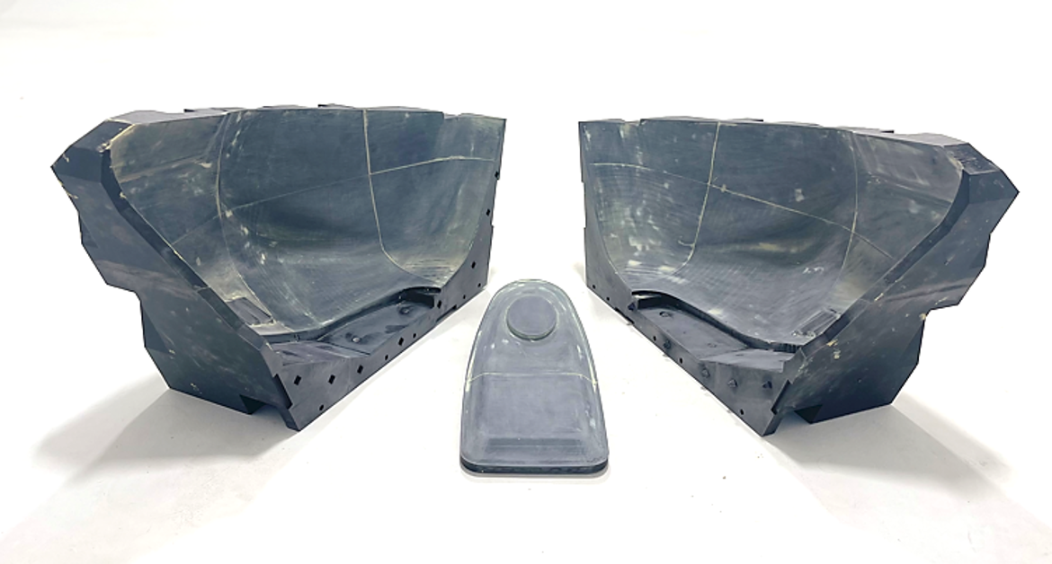 Two black plastic injection molded parts placed symmetrically, and a clear plastic cover in front of them, on a white background.