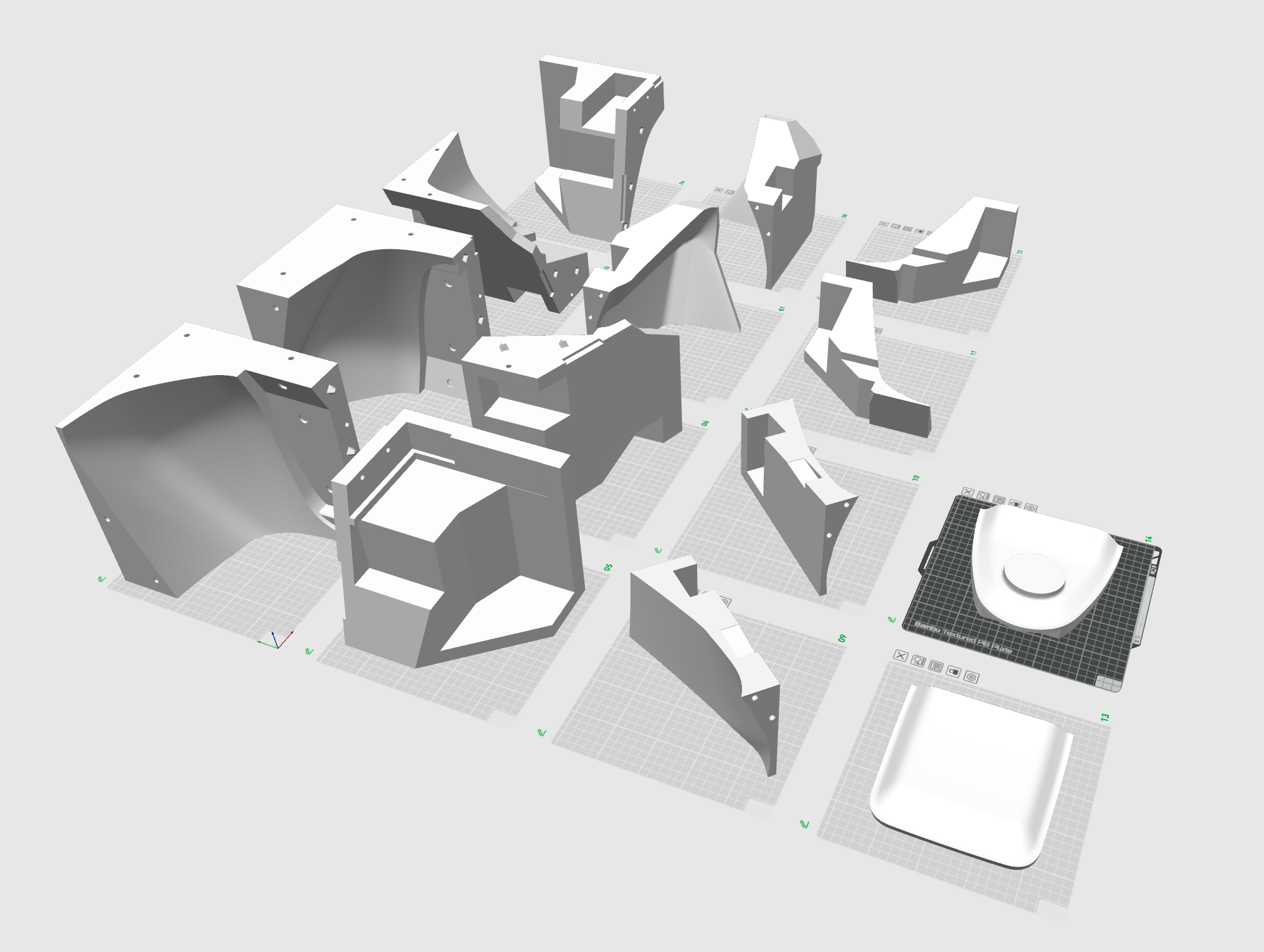 3D printed parts of a mechanical assembly on a grid, with a white plastic object on a black cutting mat at the bottom right.