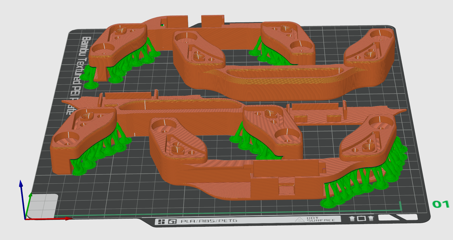 A 3D printed model of a mechanical part in orange and green colors, displayed on a black grid build plate, with labels indicating the use of PLA, ABS, PETG materials, and printing settings.