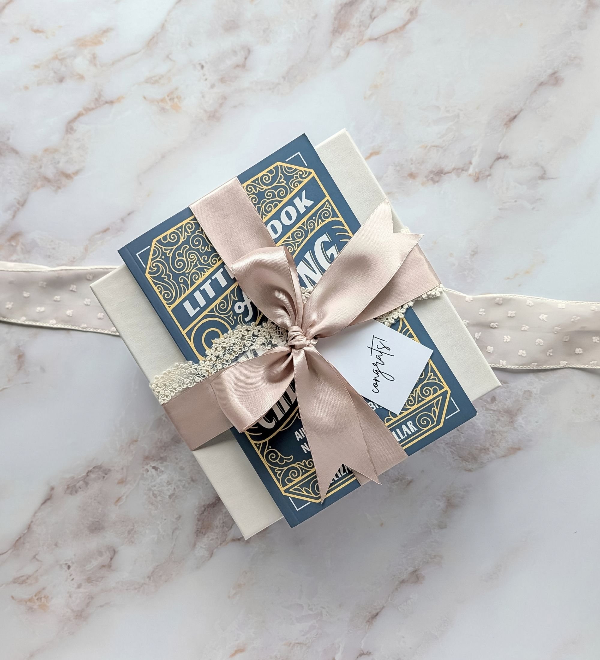 Wedding checklist book tied on a light gray linen gift box with lace ribbon, mauve satin bow, and a congrats tag for the bride‑to‑be.