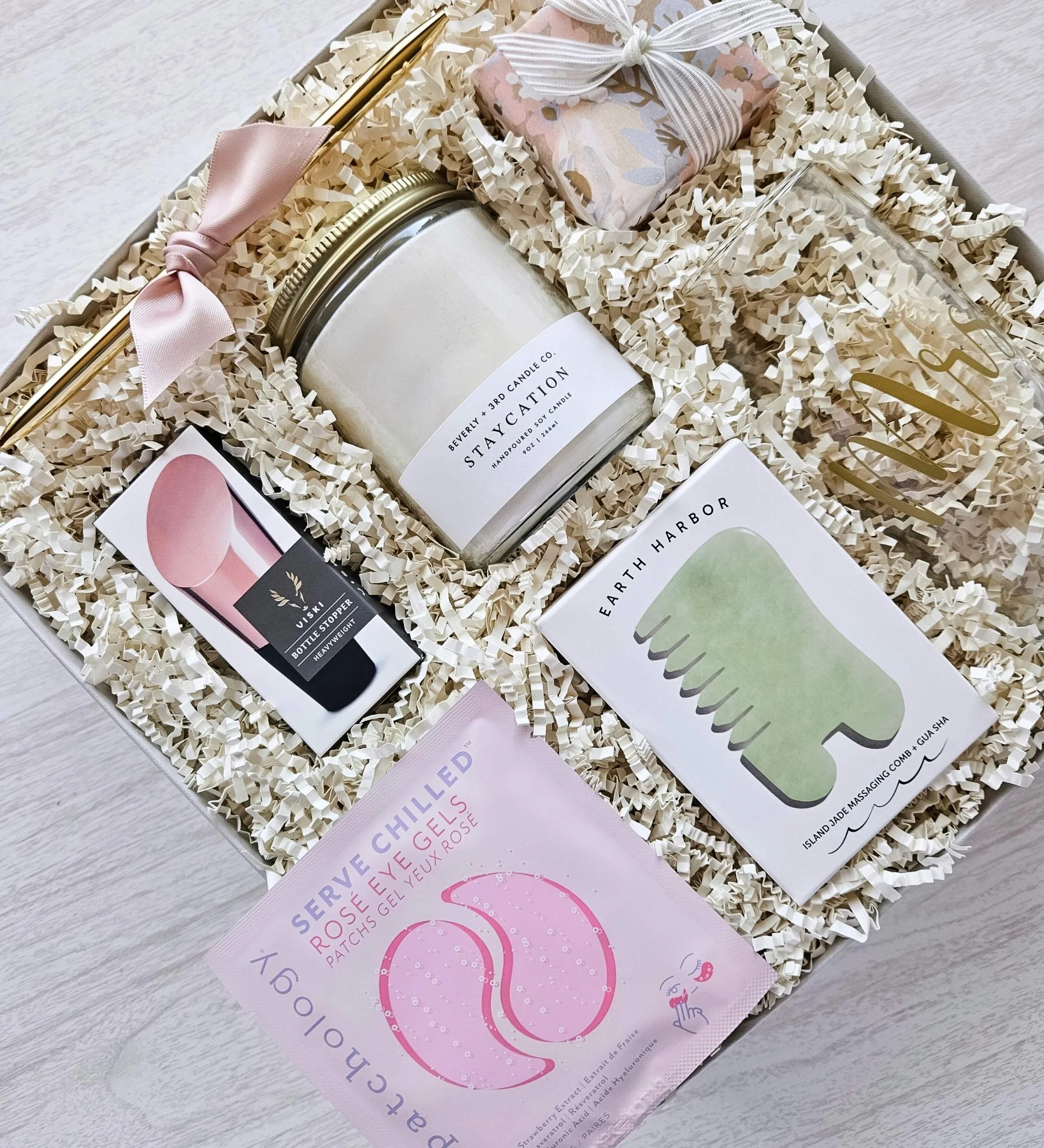 Elegant bridal shower gift set with pampering essentials: candle, jade comb gua sha tool, rosé eye gels, wine stopper, and berry lip sleep mask