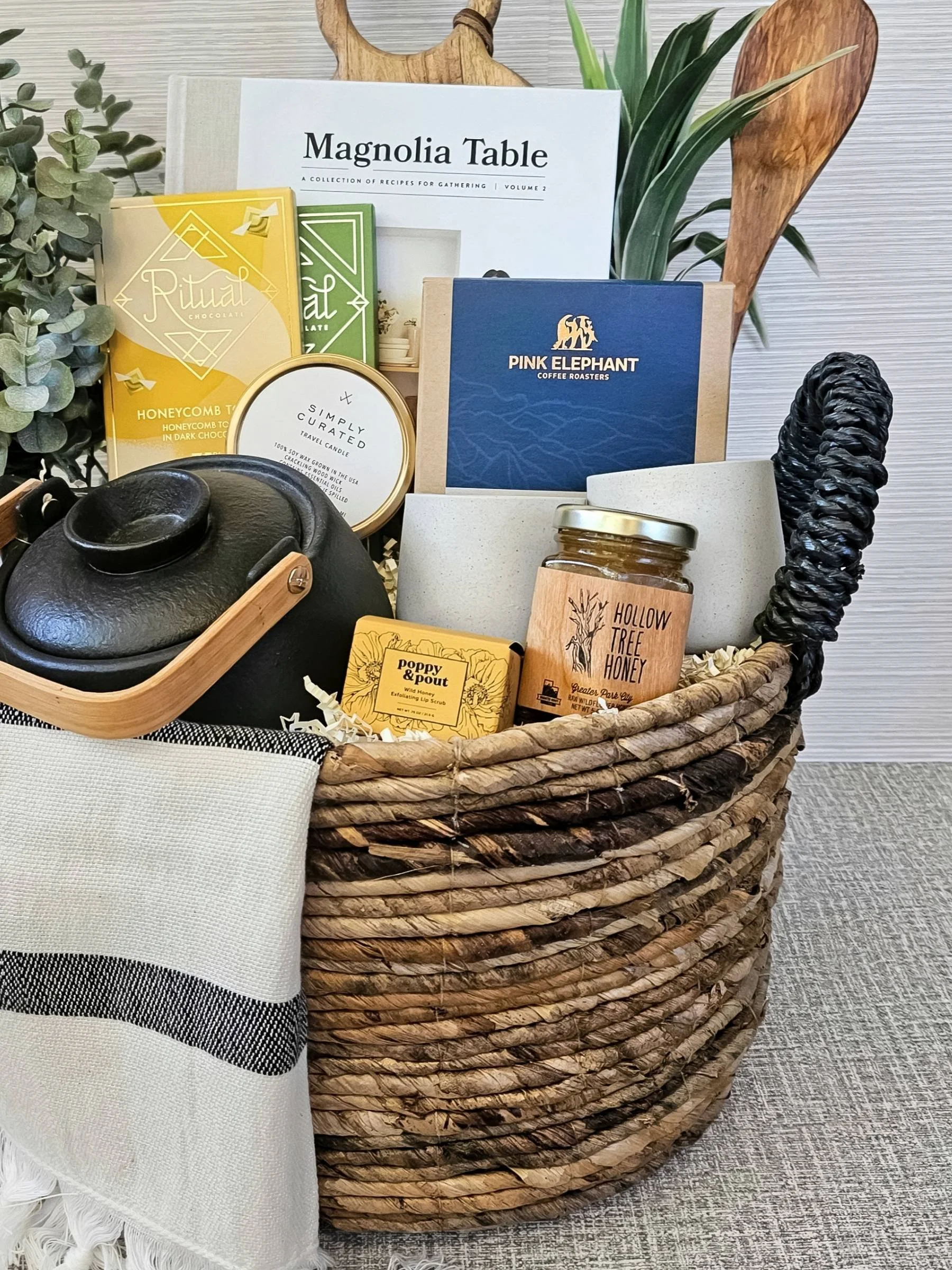 Luxury artisan gift basket featuring stoneware mugs, gourmet chocolate, wildflower honey, a travel candle, and heirloom‑quality kitchenware.