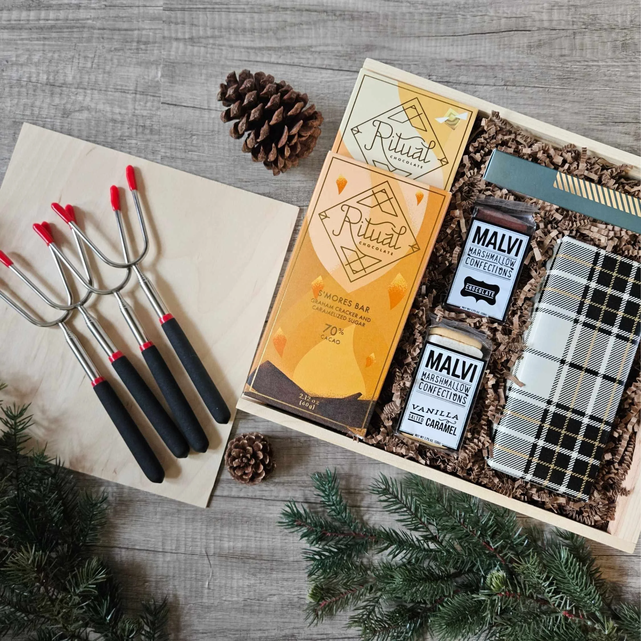 Custom campfire-inspired gift box with gourmet marshmallows, hot cocoa, graham crackers, s’more sticks, and chocolate bars—styled in a wooden box for cozy gifting and outdoor lovers.