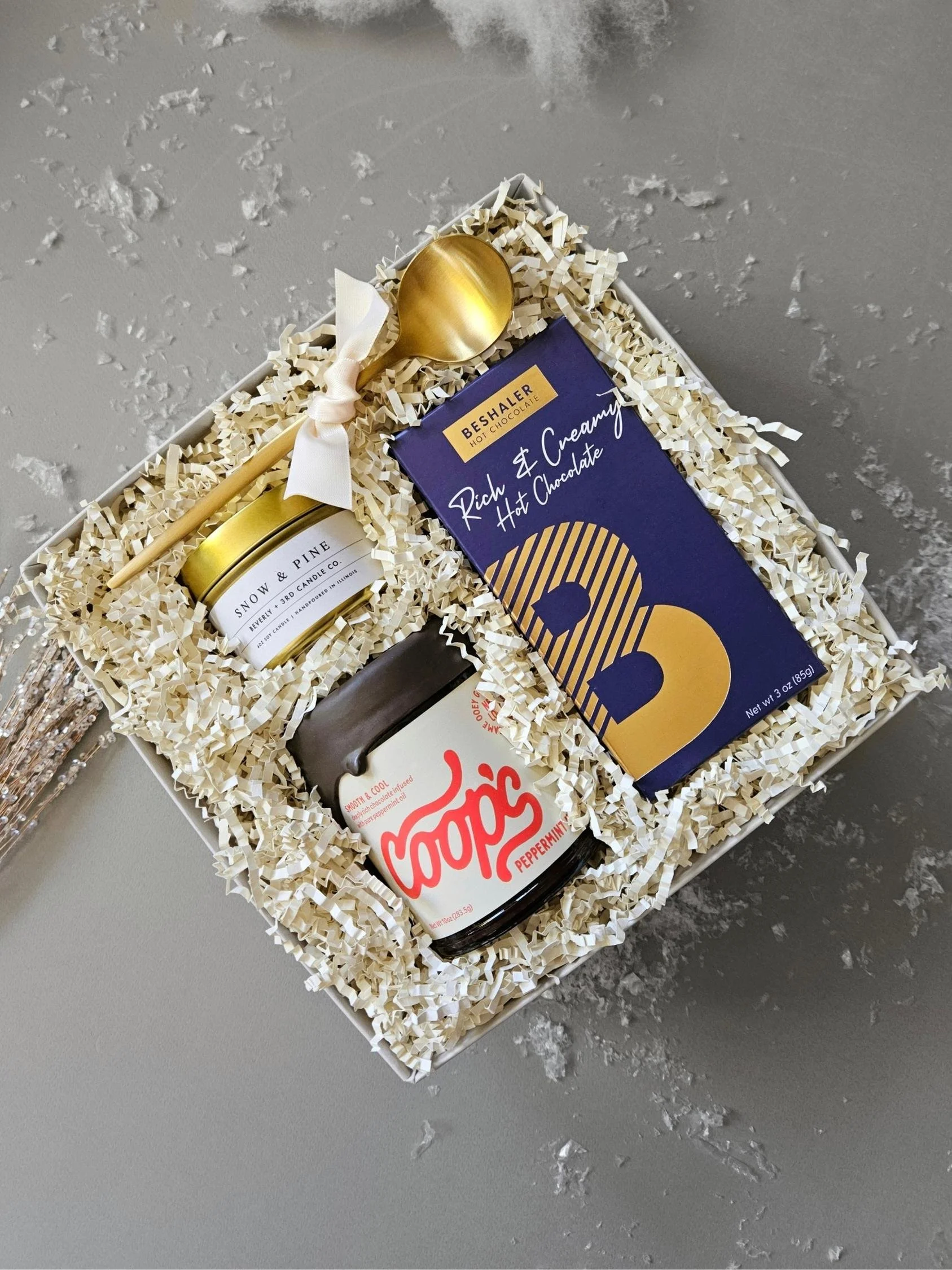 Luxury holiday gift box featuring rich and creamy cocoa mix, Coop’s peppermint sauce, Snow & Pine candle, gold spoon holiday gifting.