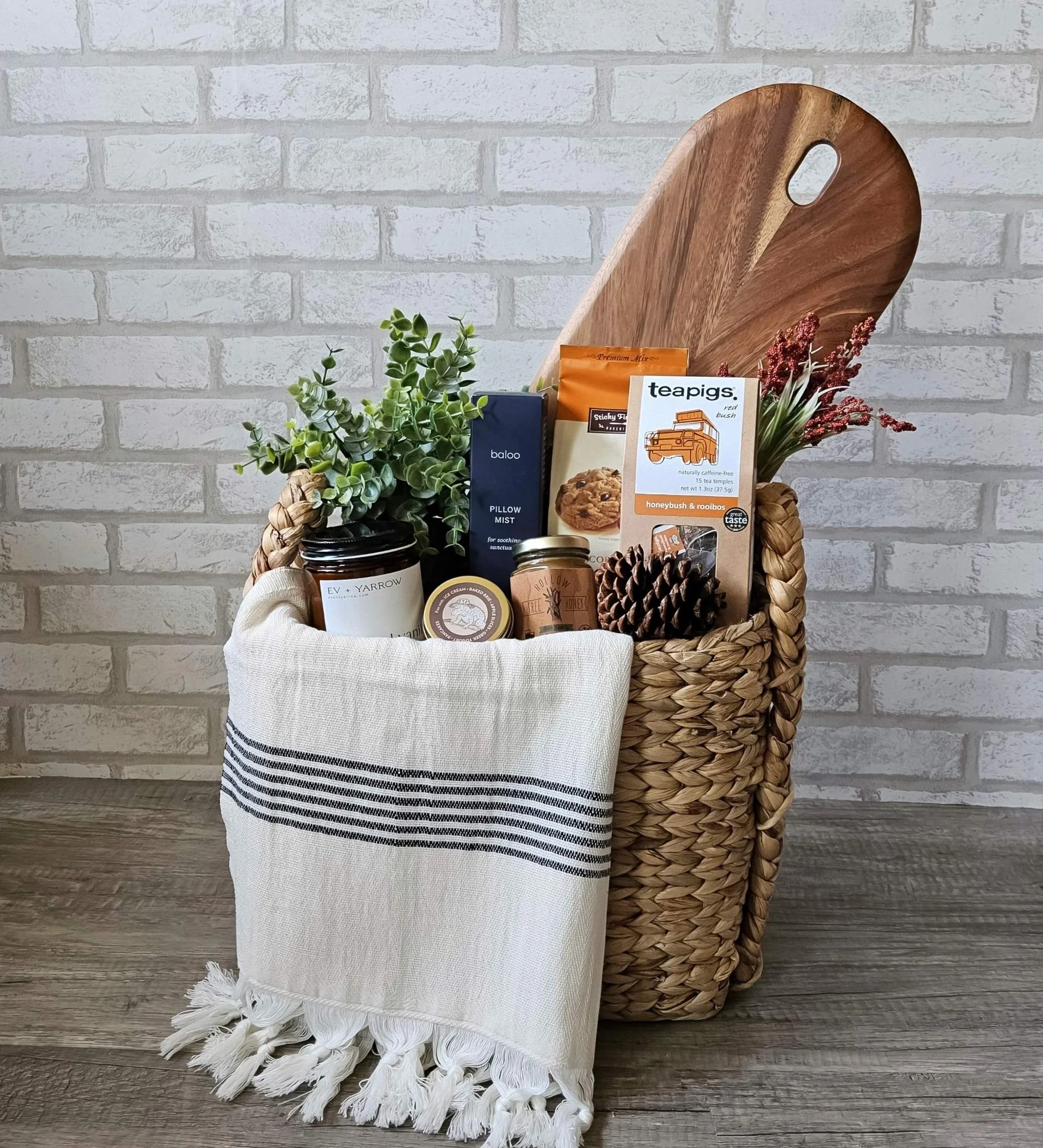 The Hearth modern rustic gift basket with Turkish towel, Indigo candle, rooibos tea, cookie mix, pillow mist, caramel sauce, and wood board.