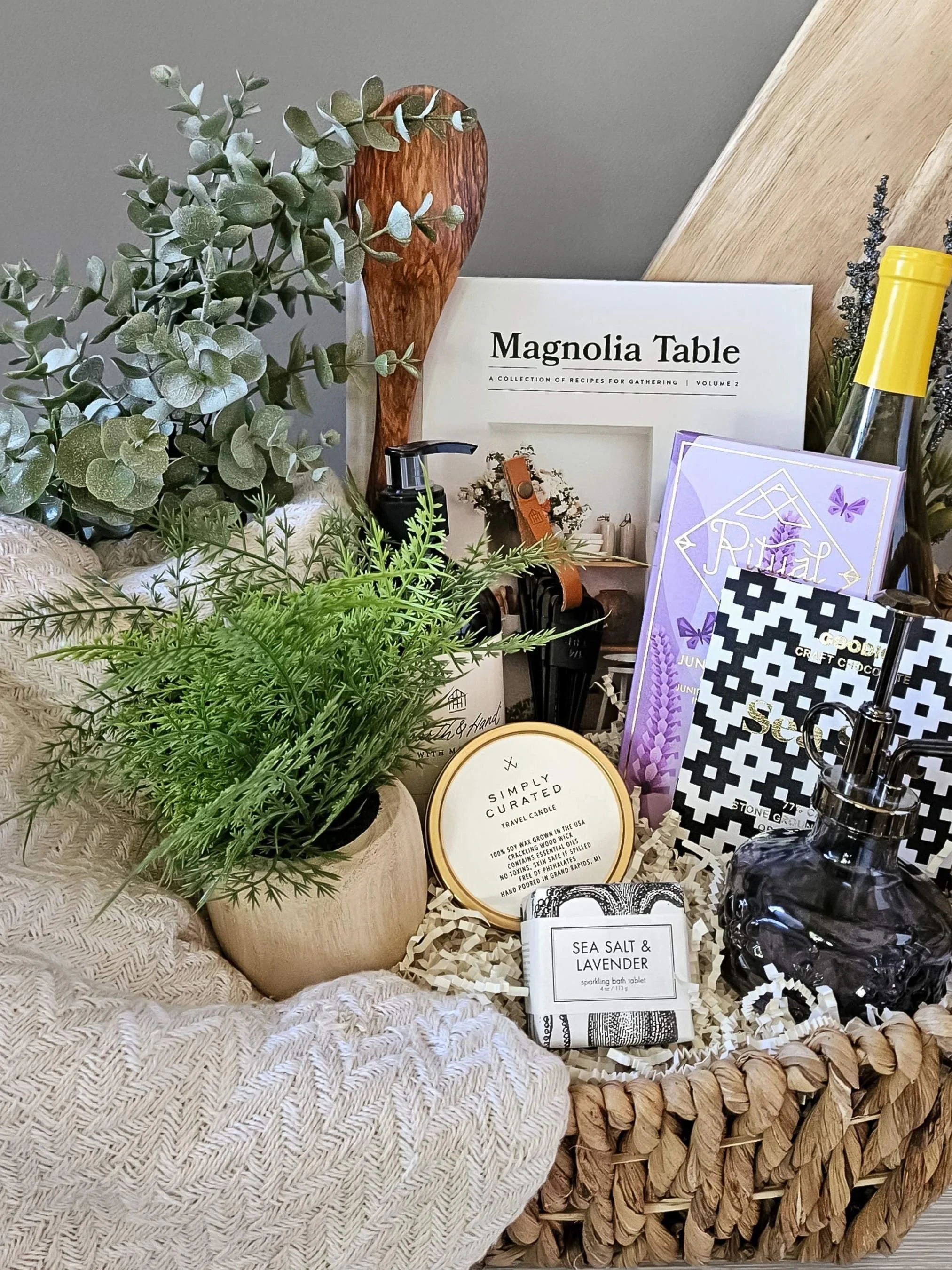 Modern home gift box including a Turkish throw, gourmet chocolate, bath bomb, candle, plant mister, and beautifully crafted kitchen accents.
