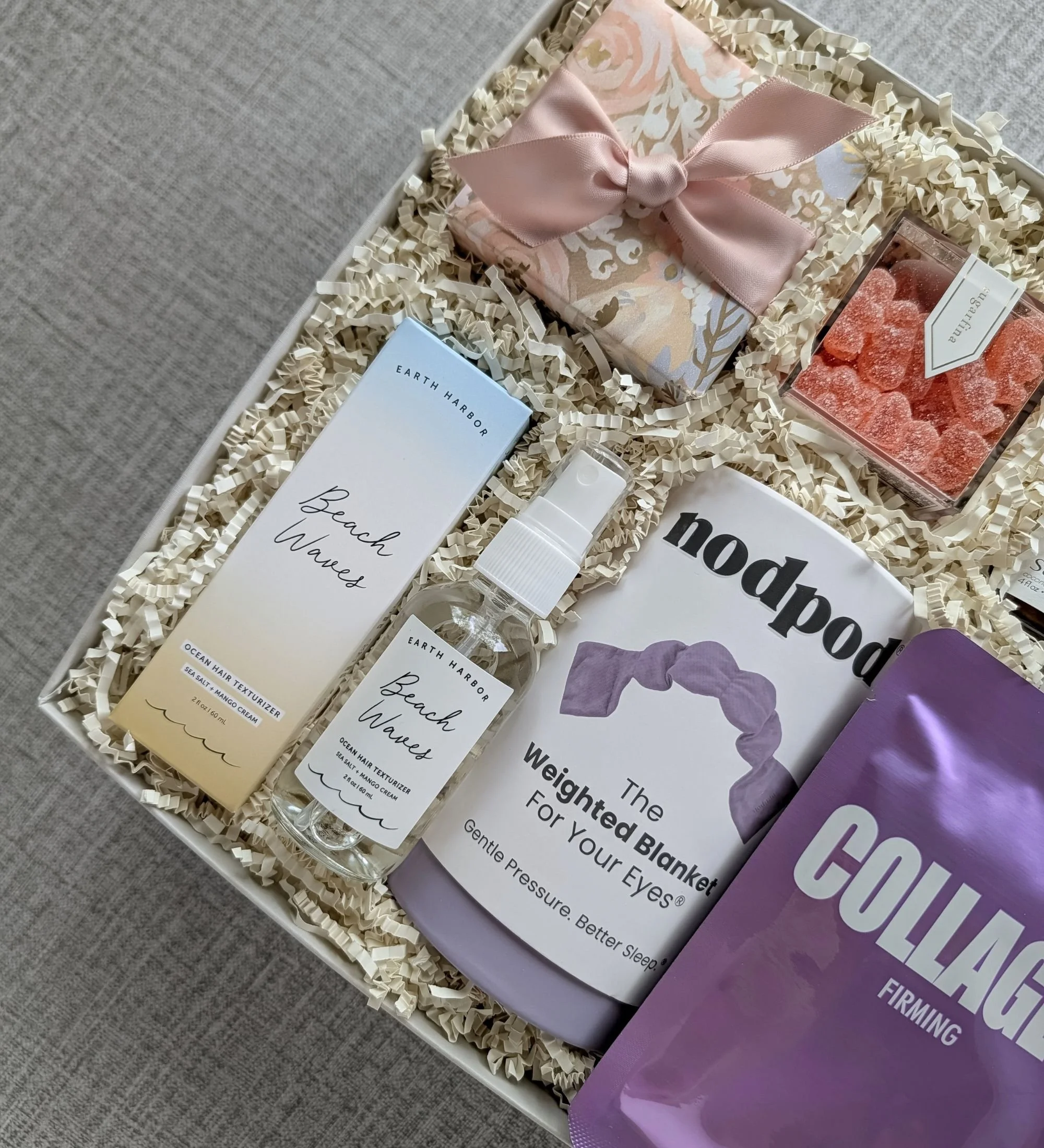 Self‑care gift box with beach wave spray, santal candle, weighted sleep mask, collagen mask, gummies, and cooling eye patches.