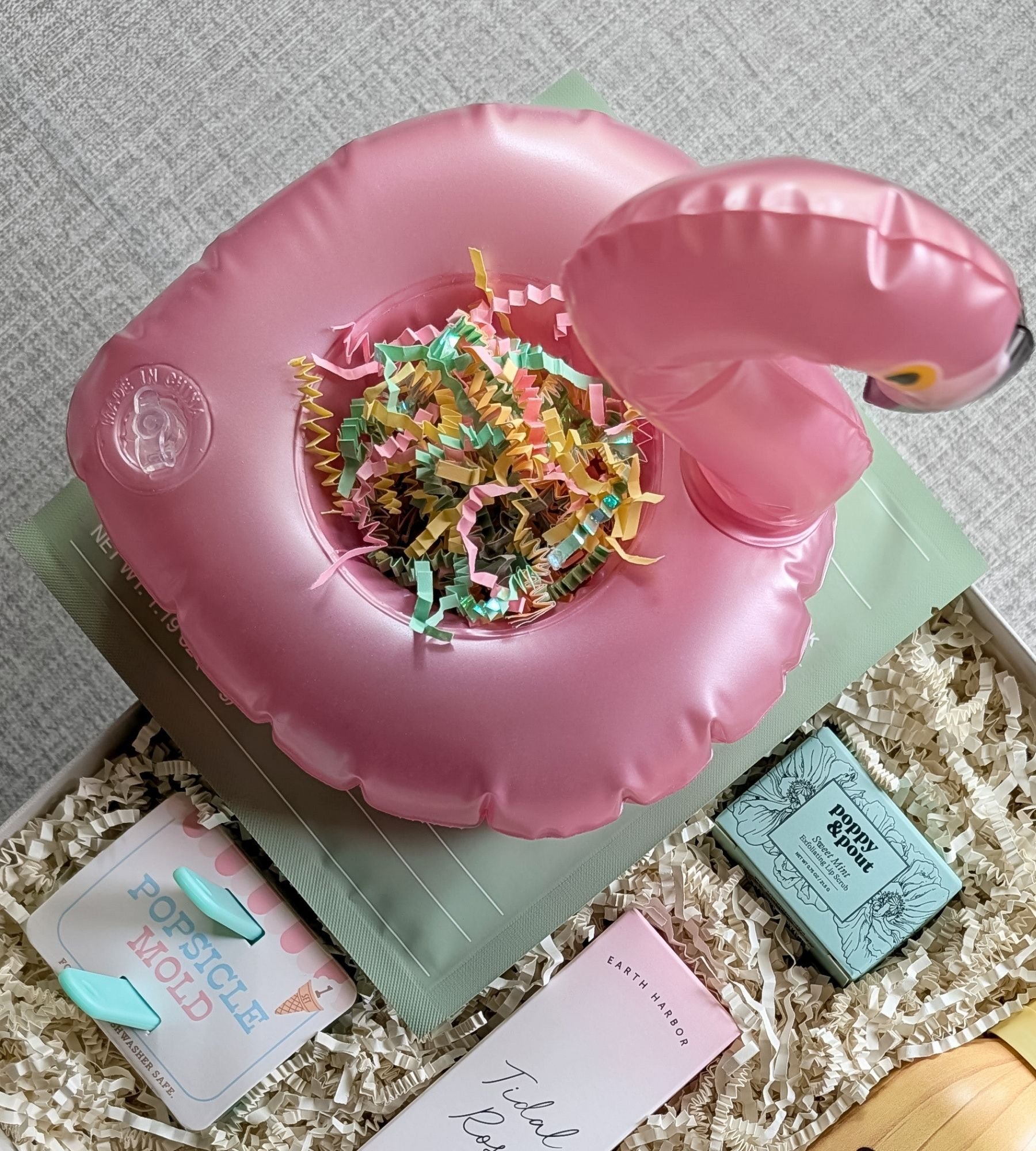 Bright summer gift set with pink flamingo drink floatie, set of two popsicle molds, after sun face mask, hydrating facial spray, and sweet mint lip scrub.