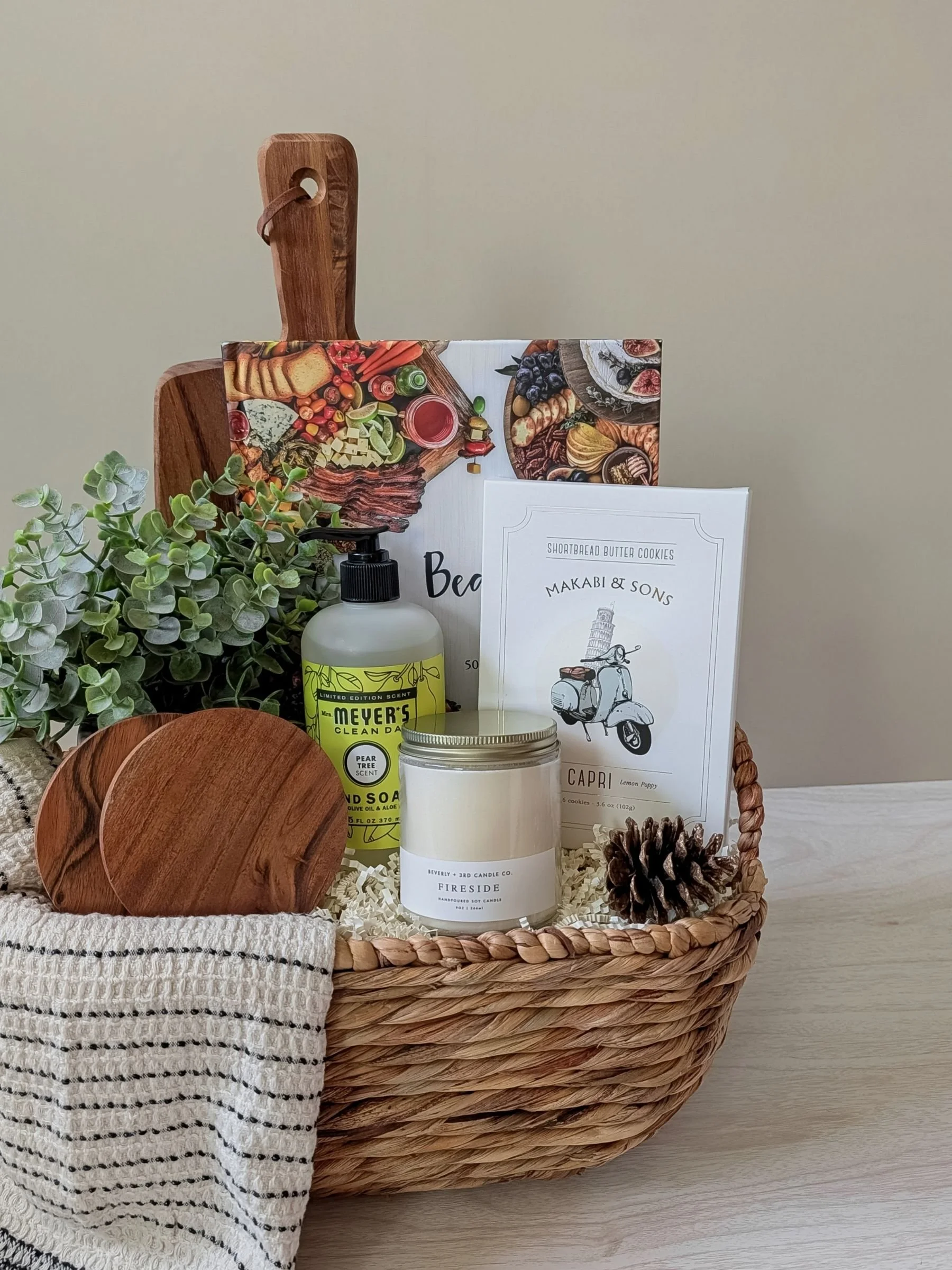 Curated gift basket with serving board, candle, hand towel, and minimalist home details designed for housewarmings and client gifting.
