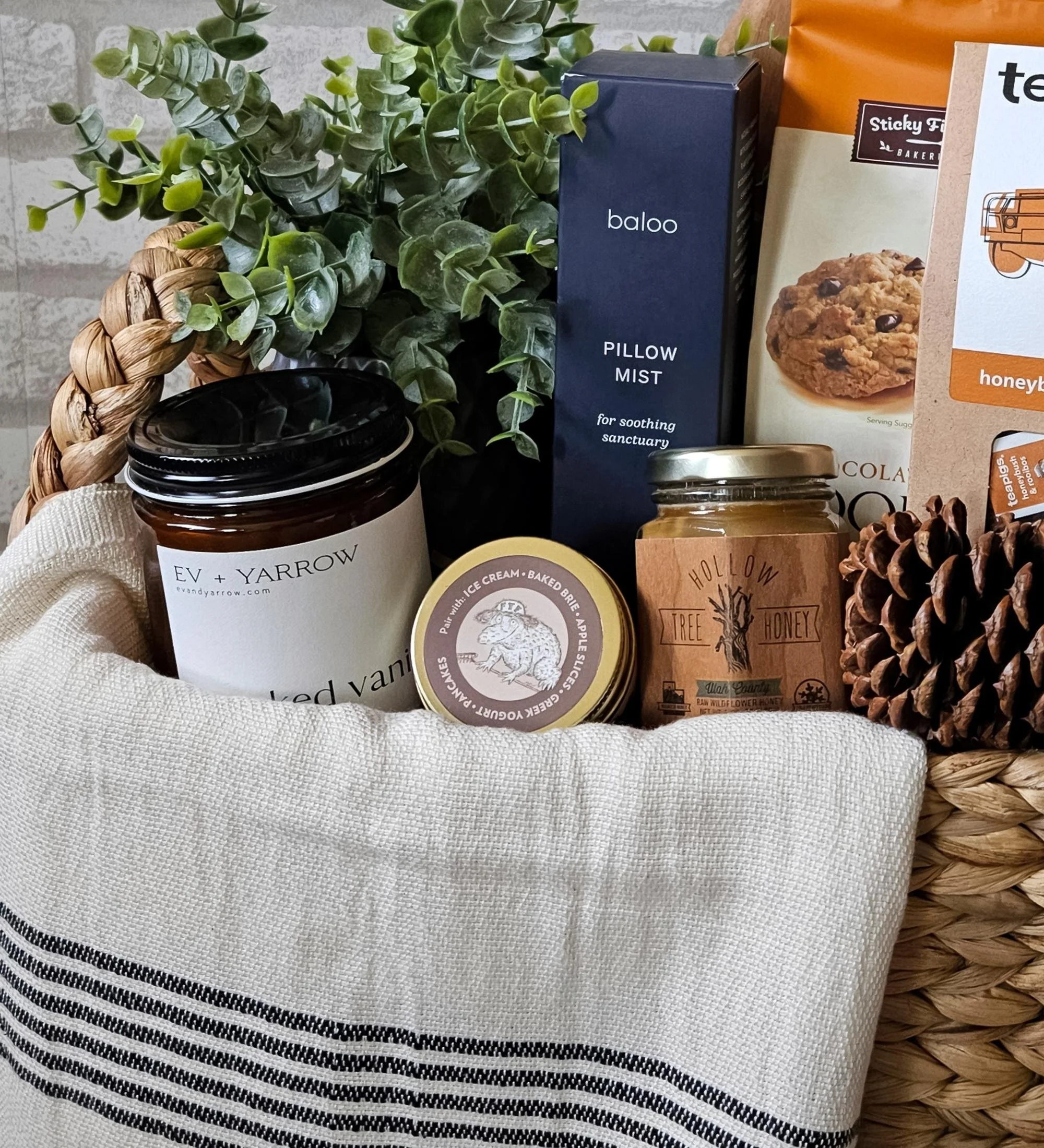 The Hearth gift basket with Turkish towel, candle, rooibos tea, cookie mix, pillow mist, caramel sauce, and seasonal florals for new homeowners.