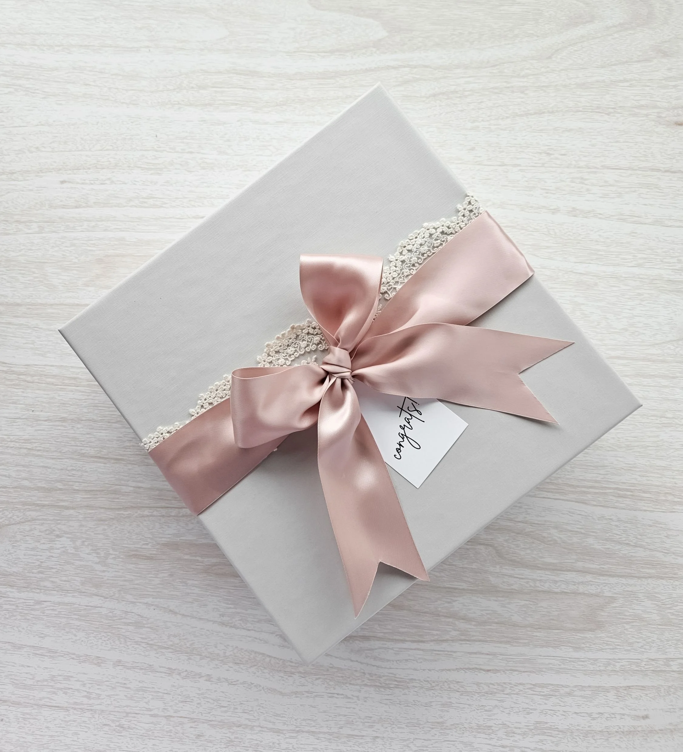 Luxury grey linen gift box tied with double satin blush ribbon, and lace. Elegant bridal gifts by Harper and James