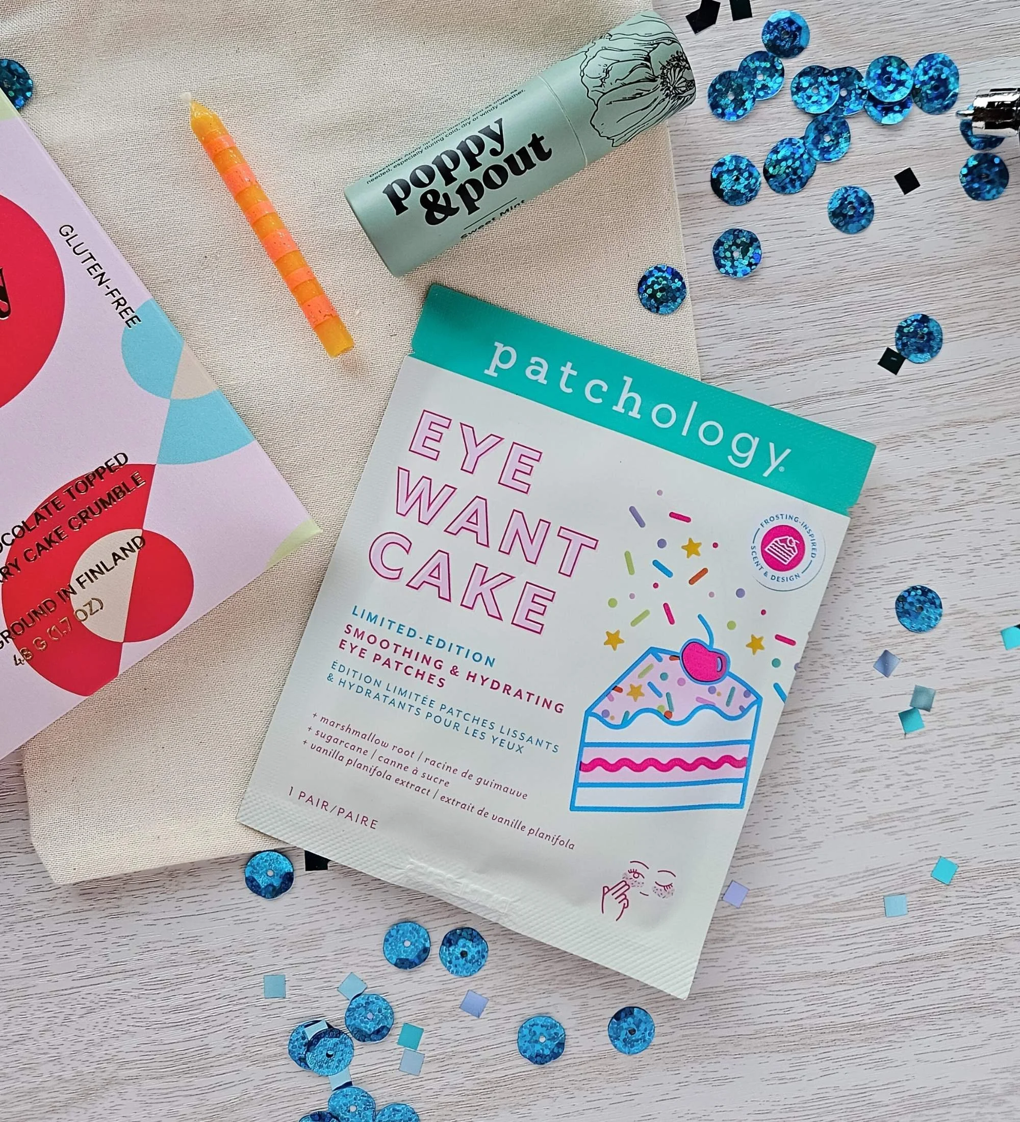 Colorful birthday candle, cake chocolate bar, eye gels, and lip balm arranged for the Make a Wish gift bag.