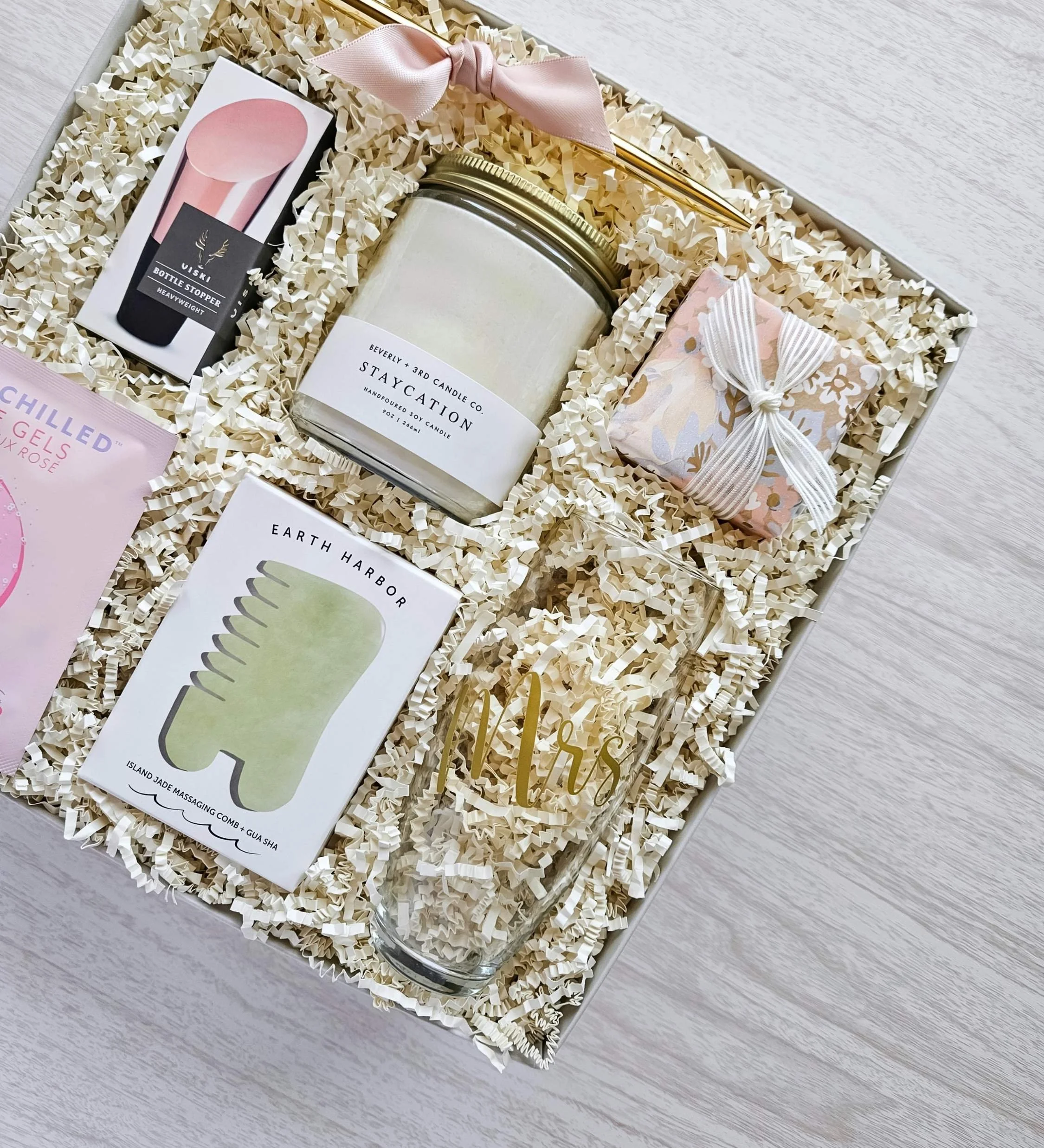 Thoughtful bride‑to‑be gift box including candle, jade comb gua sha tool, rosé eye gels, wine stopper, and Laneige lip sleep mask.