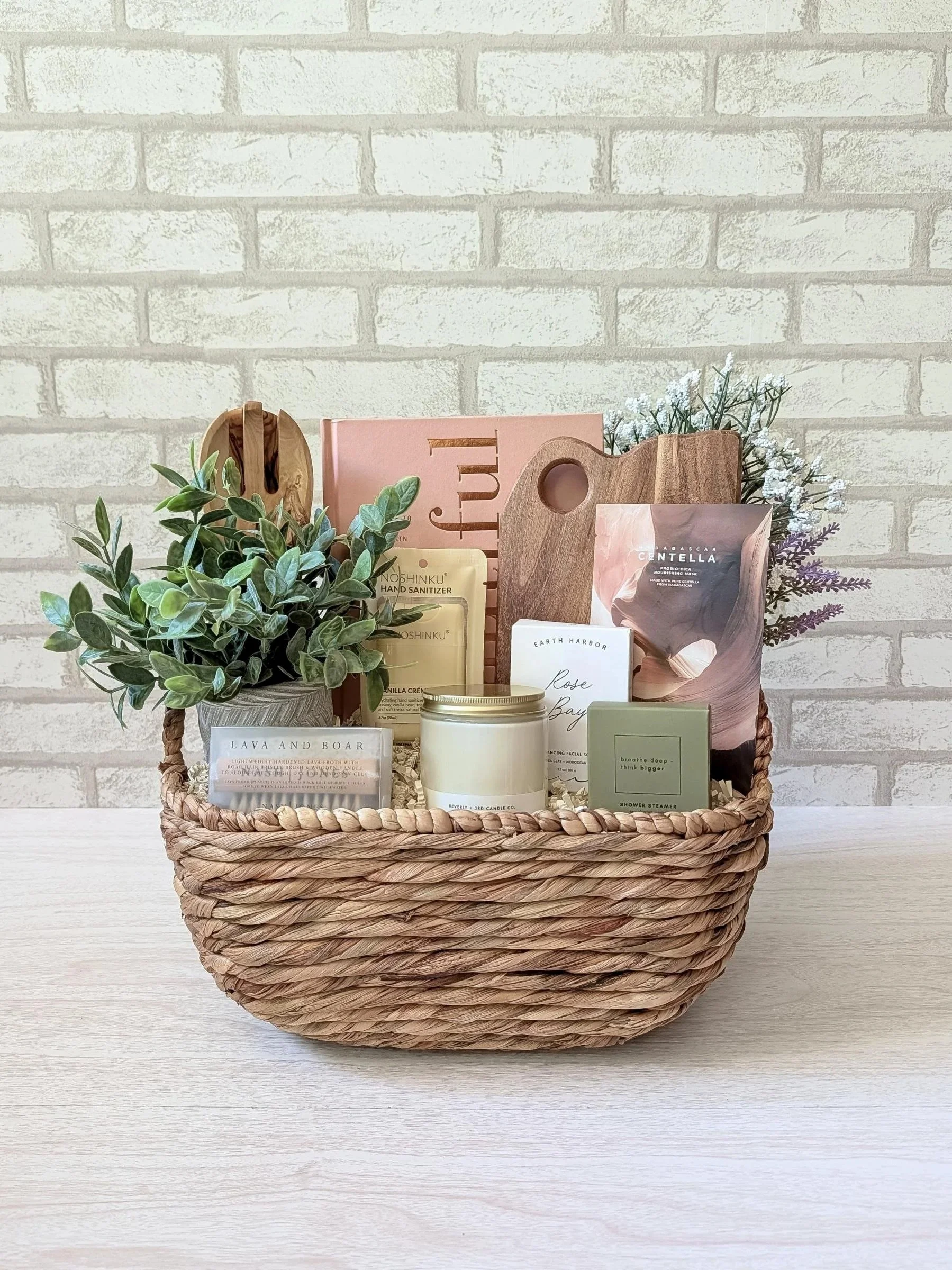 Luxury selfcare and wellness gift basket with an Eat Beautiful cookbook, candle, shower steamer, skincare and wellness items, and wooden kitchen pieces.