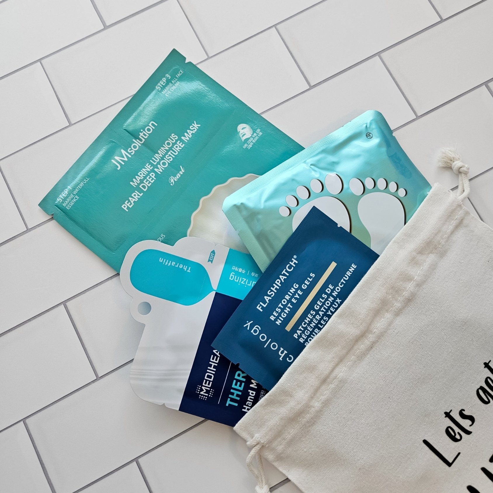 A skincare gift bag with a moisturizing 3 step face mask, restoring night eye gels, and a hydrating hand and foot mask. .