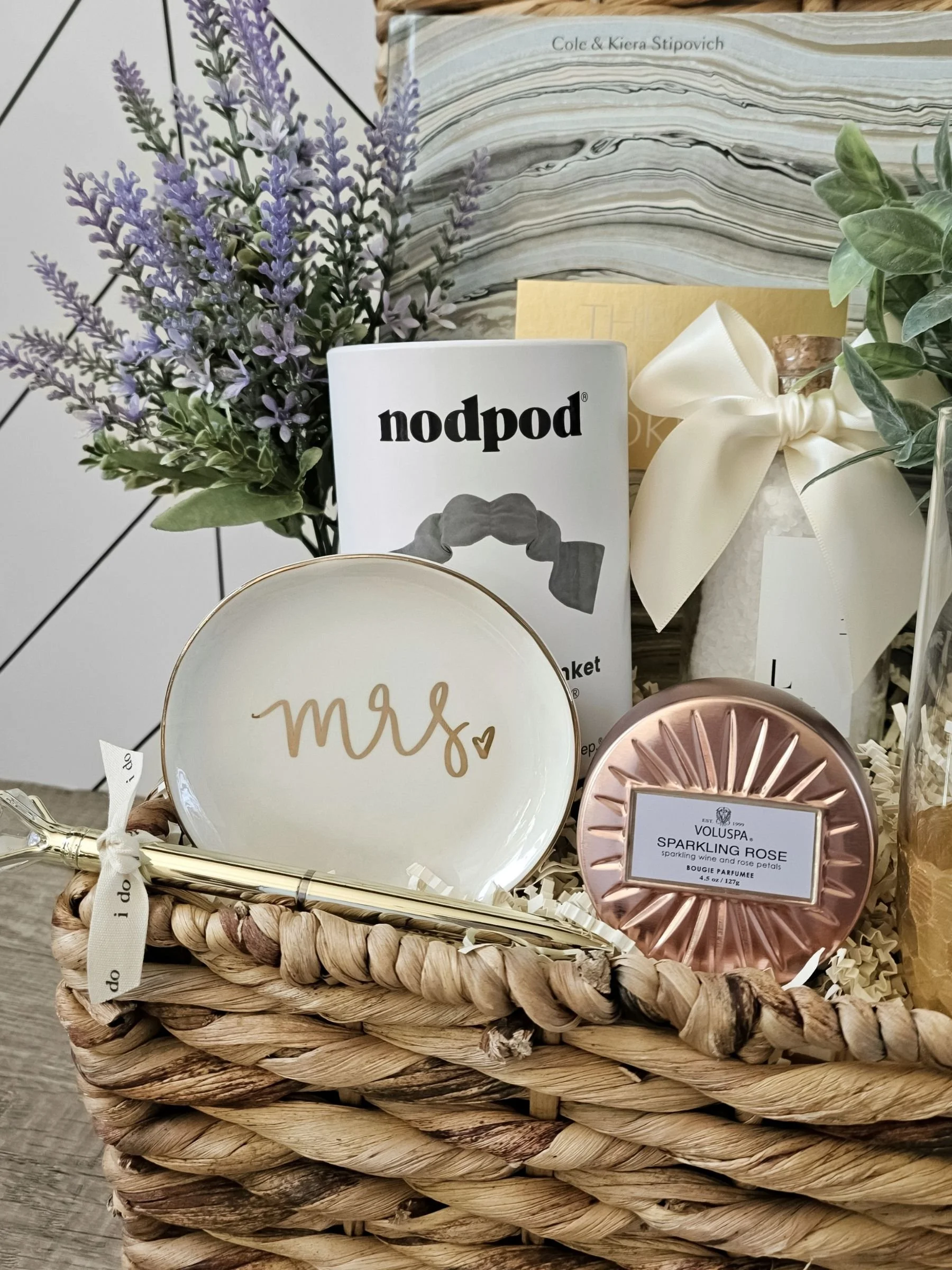 Curated bridal gift box including a ring dish, sleep mask, lavender bath salts, rose candle, champagne flutes, diamond pen, and romantic self‑care essentials.