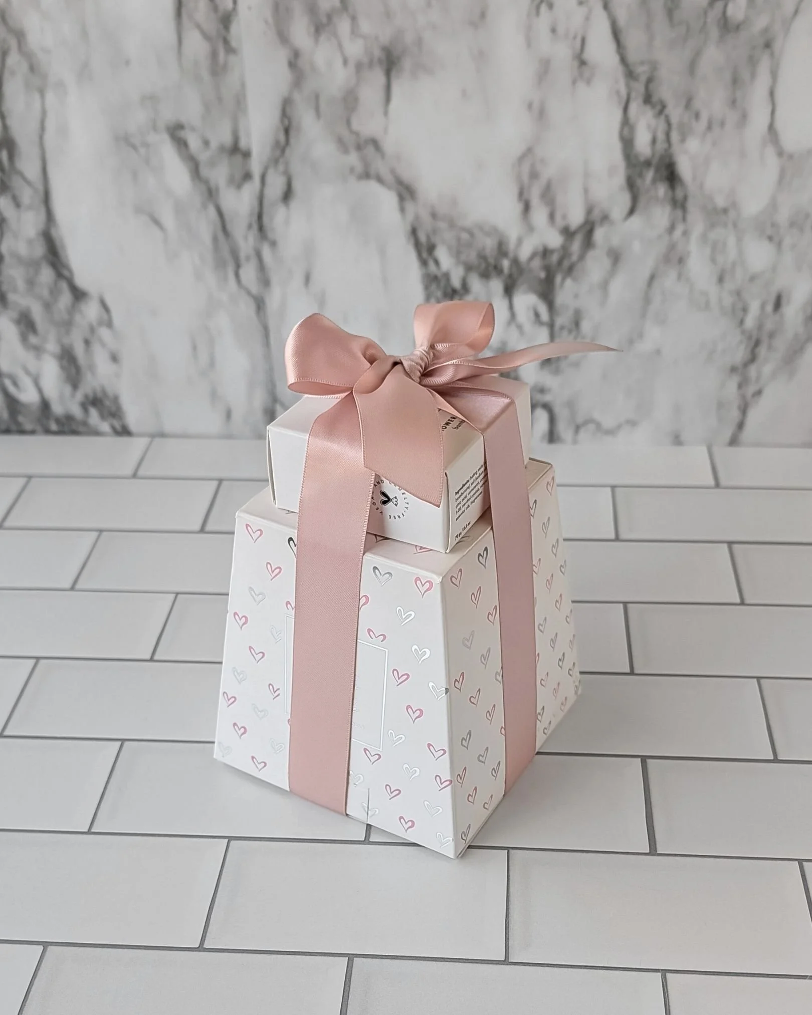 Birthday gift set with a candle and shower steamer stacked and tied with a blush satin ribbon.