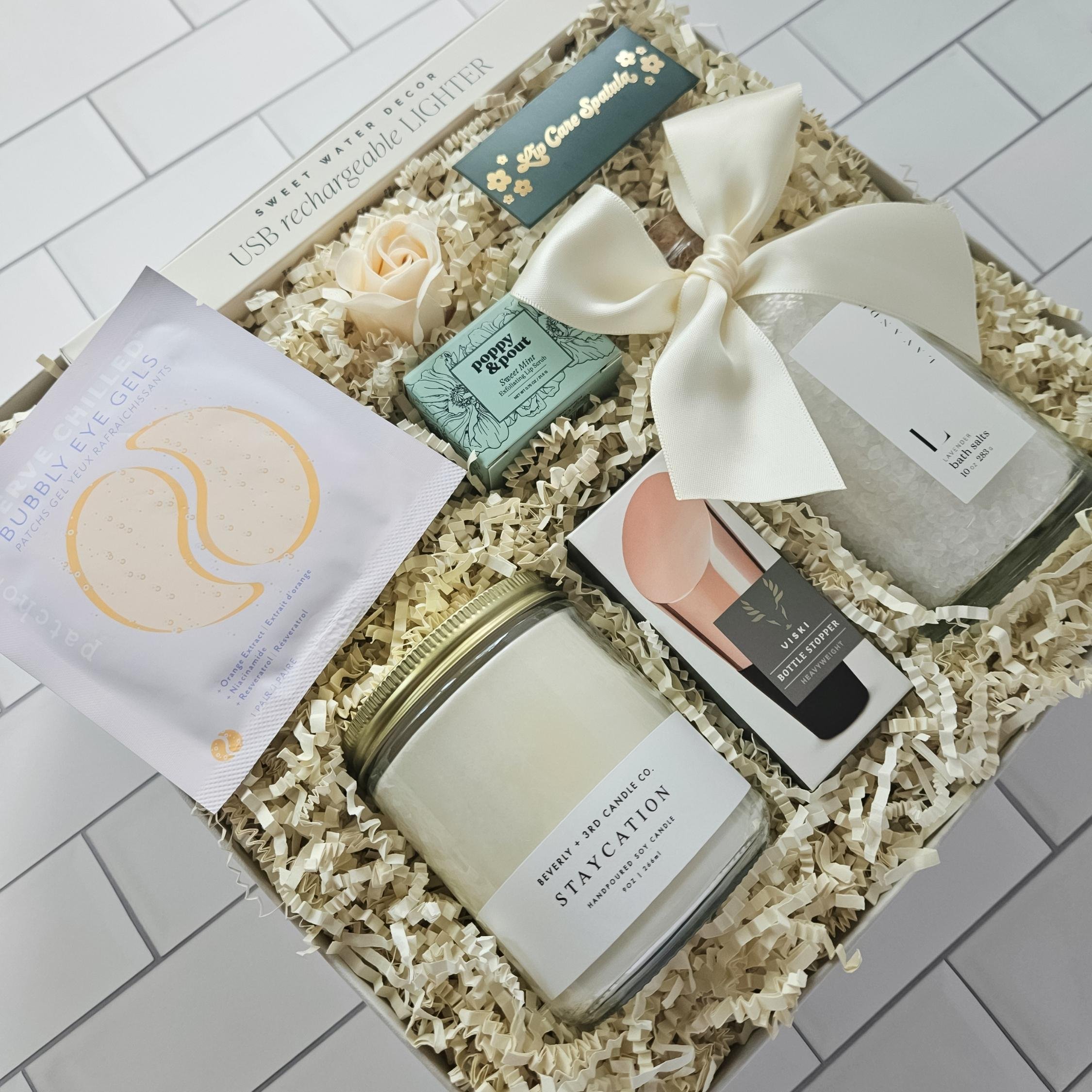 Curated gift box with facial mask, rose soap, bath item, and ‘Staycation’ candle—artfully arranged with shredded filler and a decorative card for self-care or housewarming gifting.