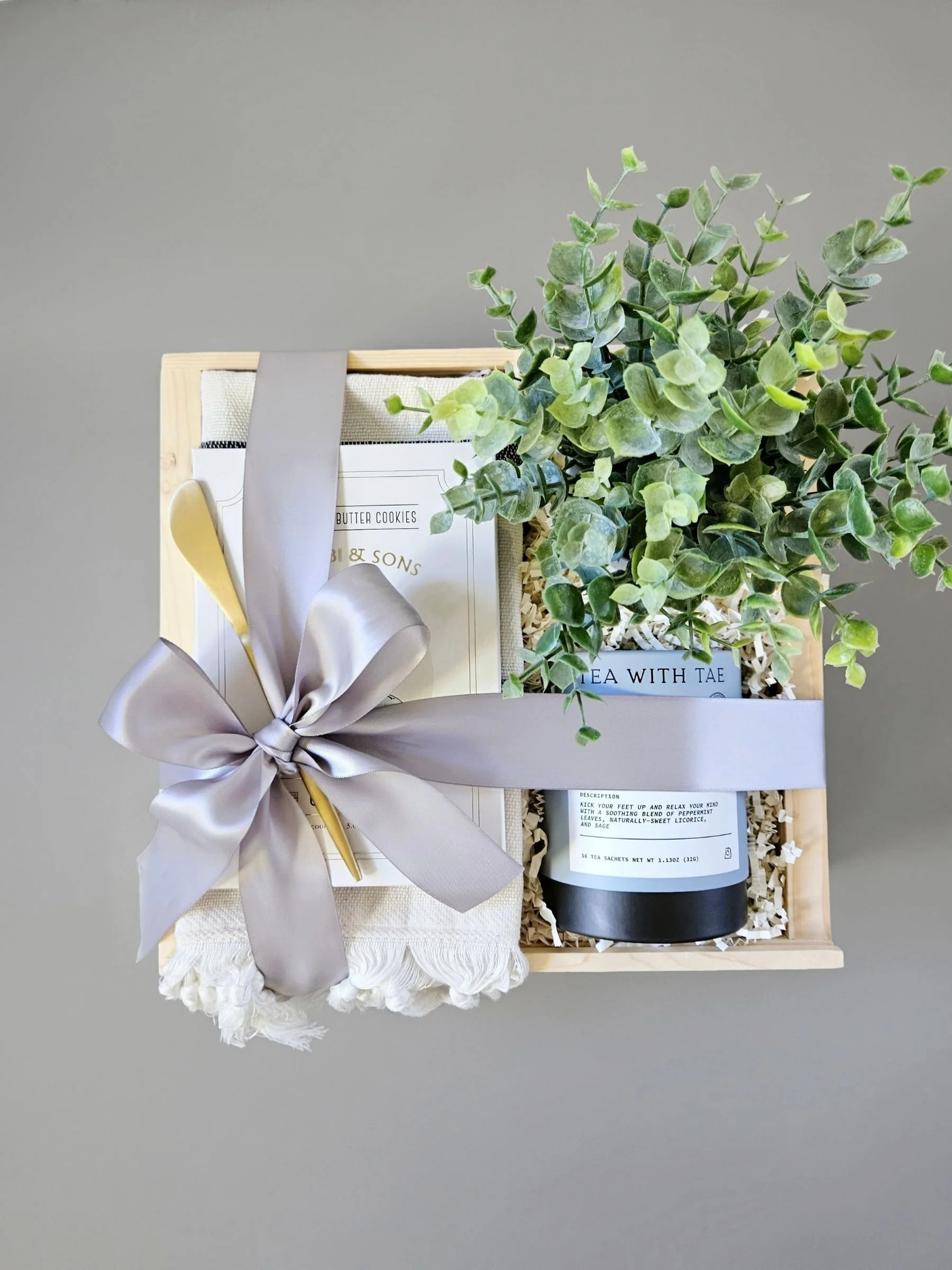 Closing gift with Calming tea, a luxe large Turkish hand towel, Makabi & sons shortbread cookies, gold spreader, and faux plant in a wood keepsake gift box