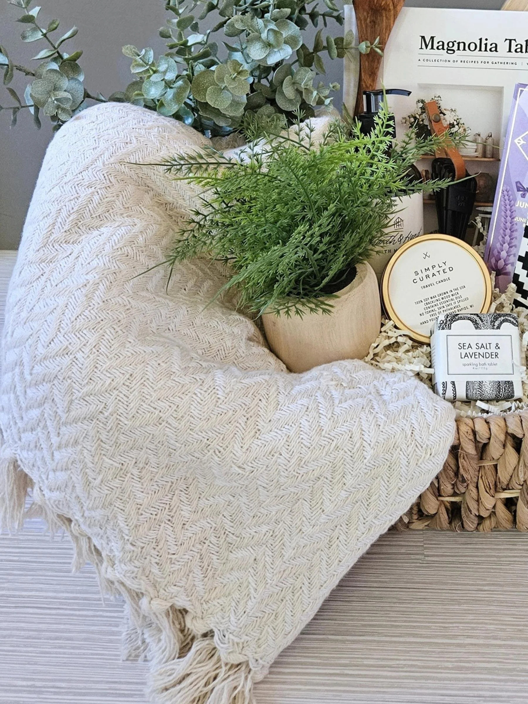 Modern home gift box including a Turkish throw, gourmet chocolate, bath bomb, candle, plant mister, and beautifully crafted kitchen accents.