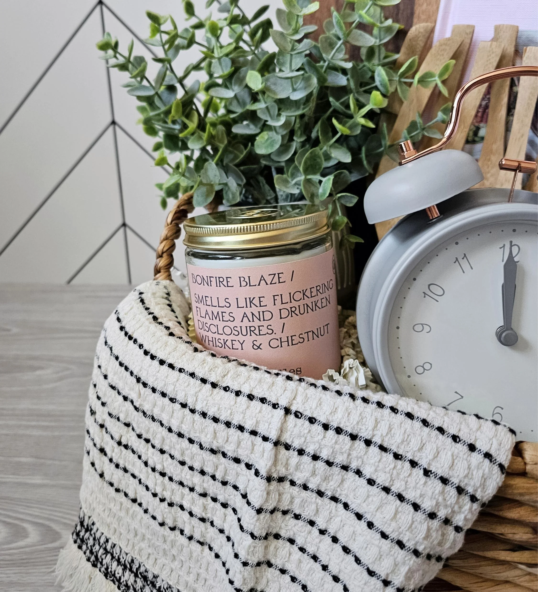 Curated spring gift basket for women with cookbook, wood board, candle, cookies, salad claws, and a textured woven hand towel.
