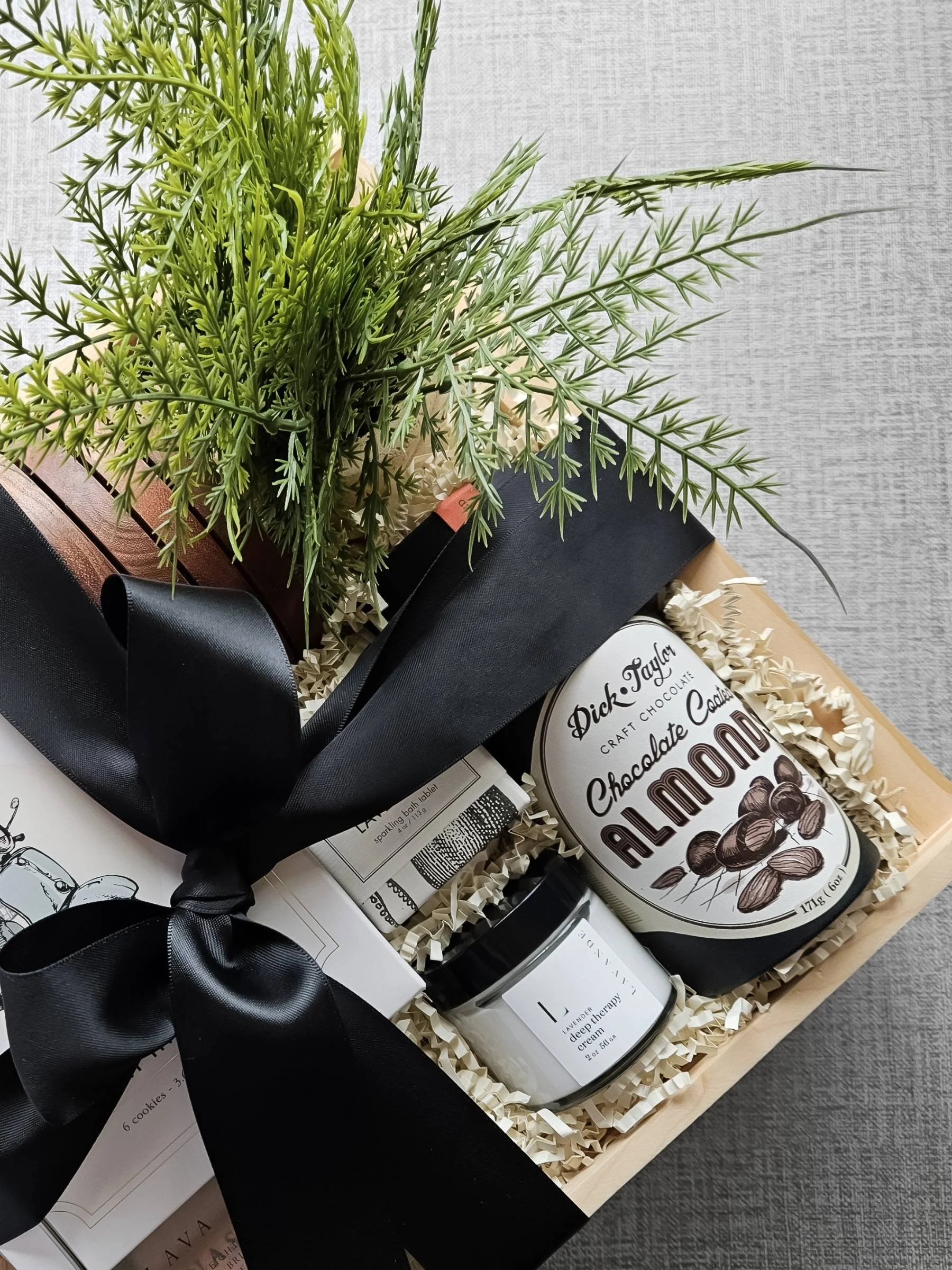 Luxury client gift with chocolate‑covered almonds, lavender hand crème, and a sea salt & lavender bath tablet, all styled in a wooden gift box.