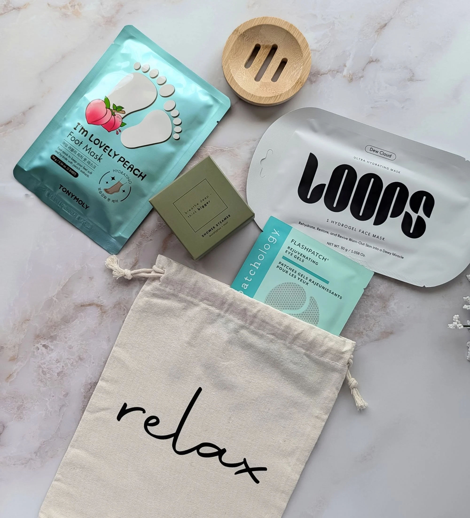 Relaxation gift bundle featuring Loops face mask, Patchology eye gels, peach foot mask, eucalyptus steamer, and bamboo tray.