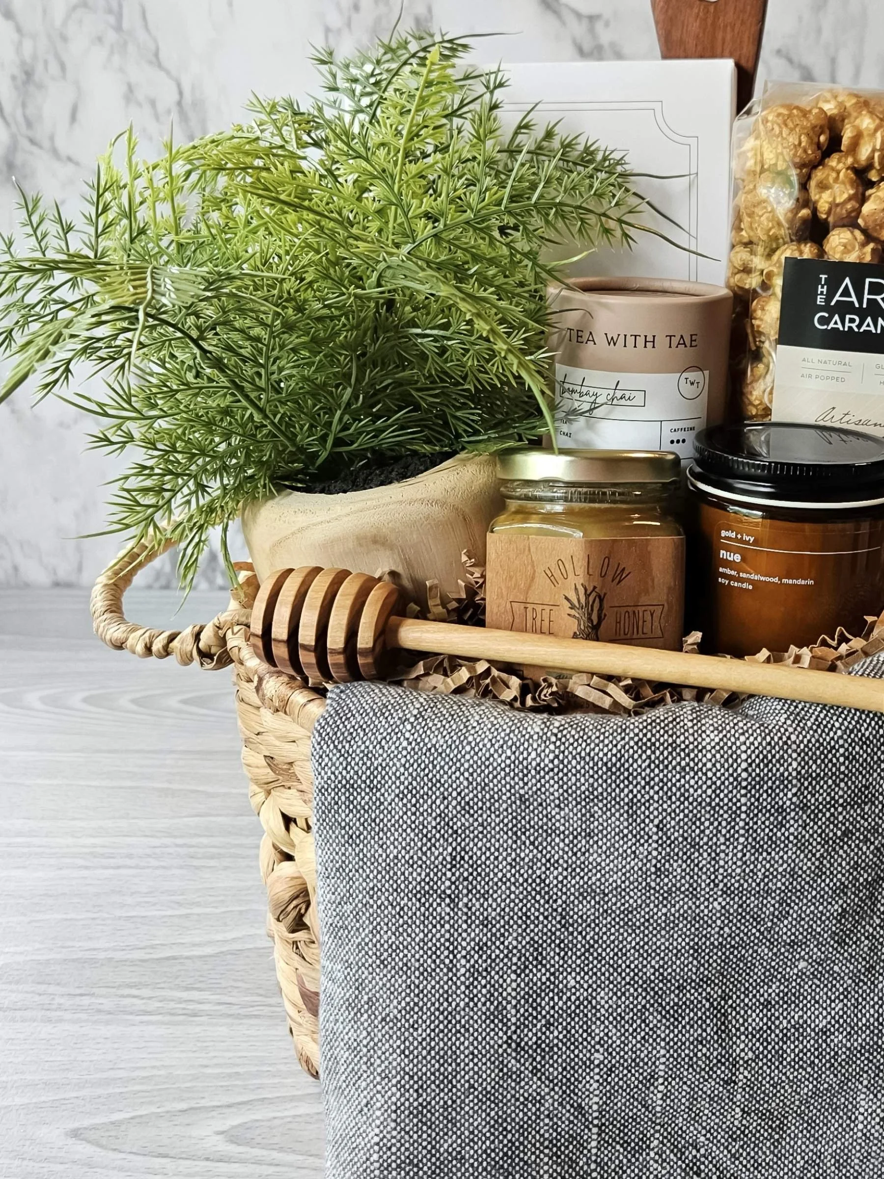 Curated Linden gift basket featuring chai tea, wildflower honey, gourmet popcorn, wood honey dipper, Nue candle, serving board, and more.
