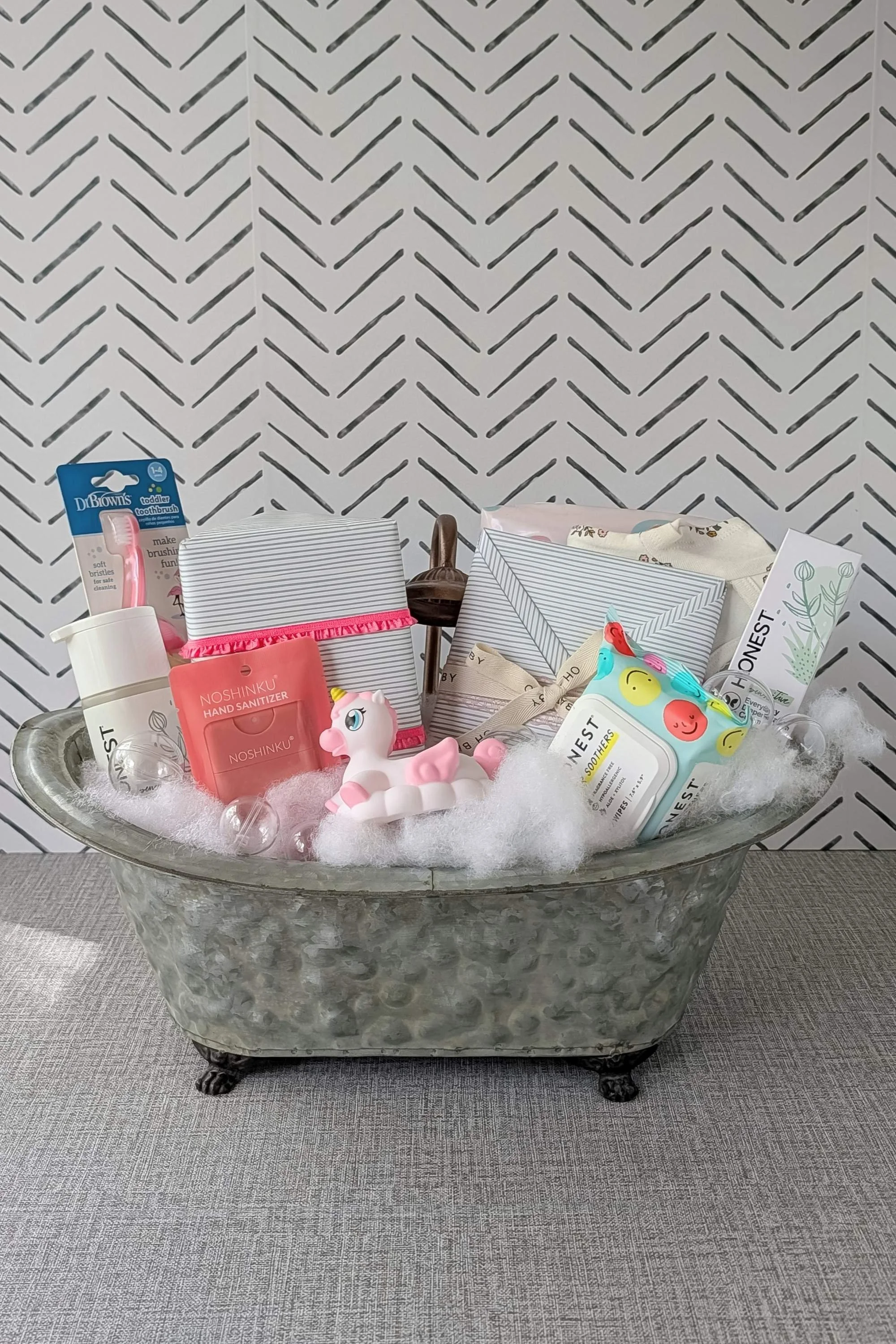 A custom baby shower gift created for a little girl, designed with a sweet bath‑time theme. This vintage metal tub is filled with clean bath essentials, Honest shampoo and lotion, Little Noses wipes, a unicorn bath thermometer, princess bath toys, a 