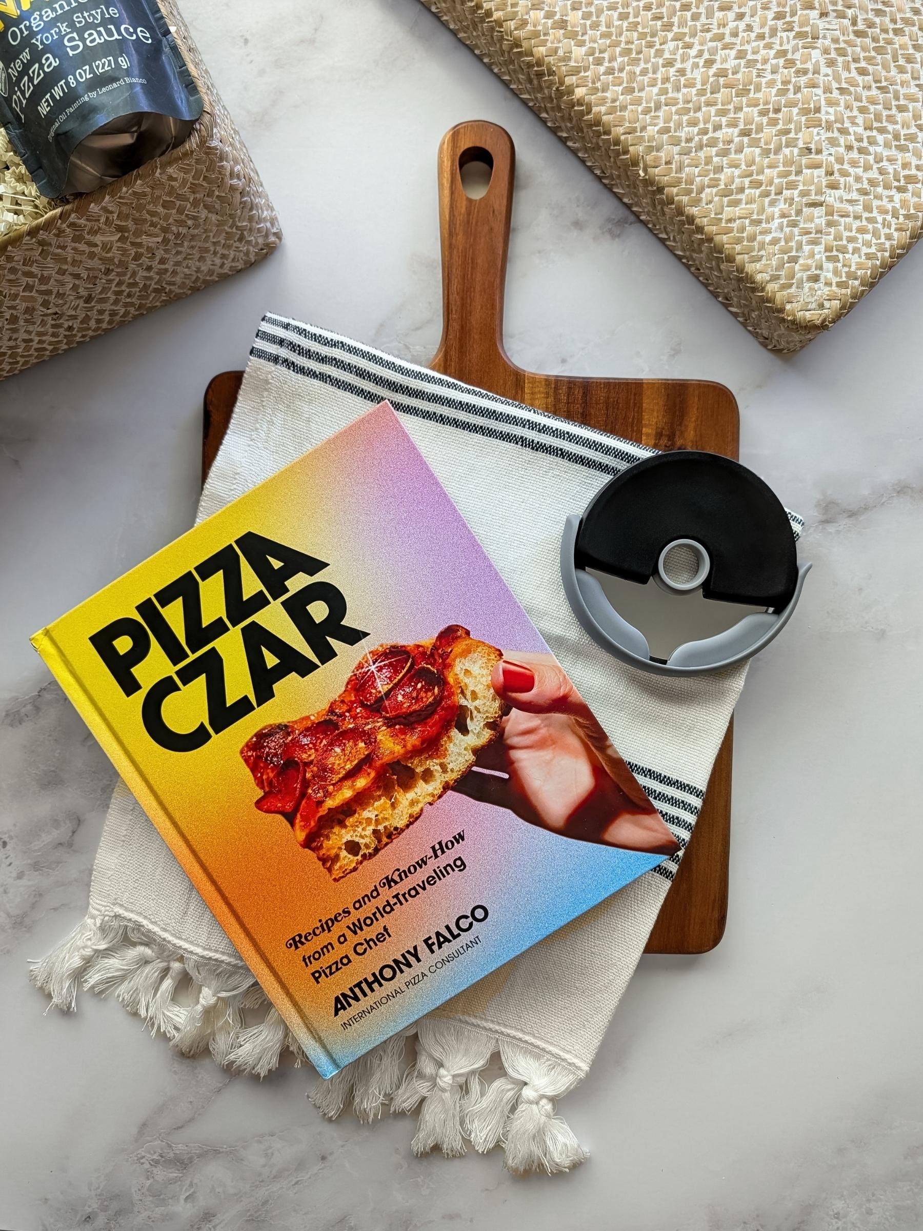 A gourmet fun Pizza Night gift basket featuring a Pizza Czar cookbook, pizza wood board, modern pizza cutter, and striped Turkish hand towel.
