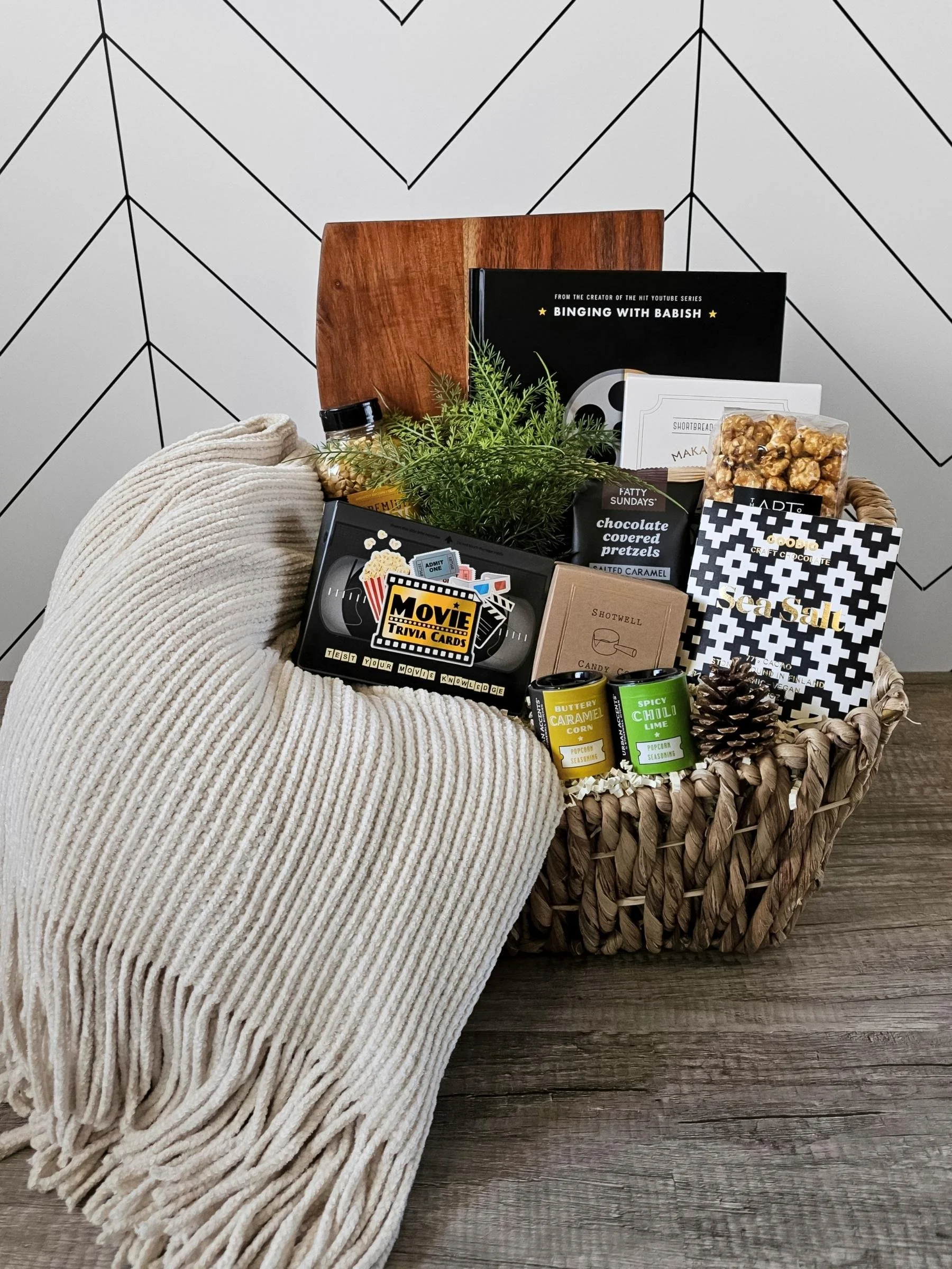 Elegant movie‑night gift basket with a cozy throw, gourmet popcorn, artisan sweets, a film‑themed cookbook, and entertaining trivia cards.