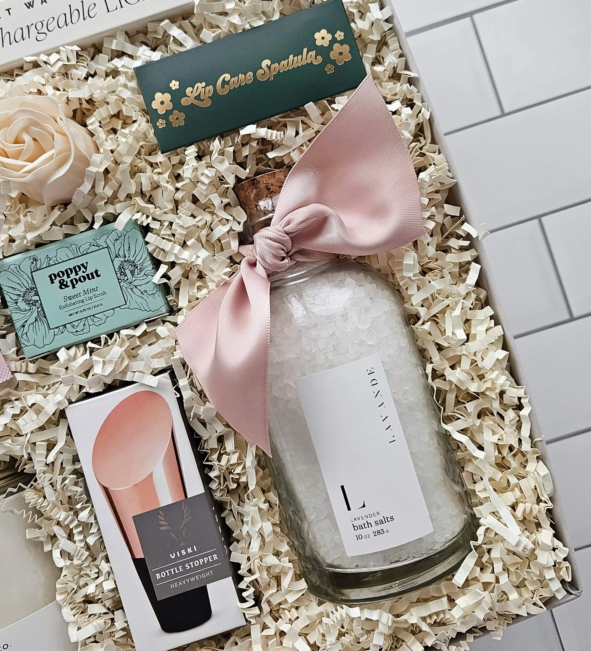 Luxury gift box for her with lavender bath salts, a rose gold wine stopper, sweet mint lip scrub with a gold flower spatula, and a USB rechargeable lighter.