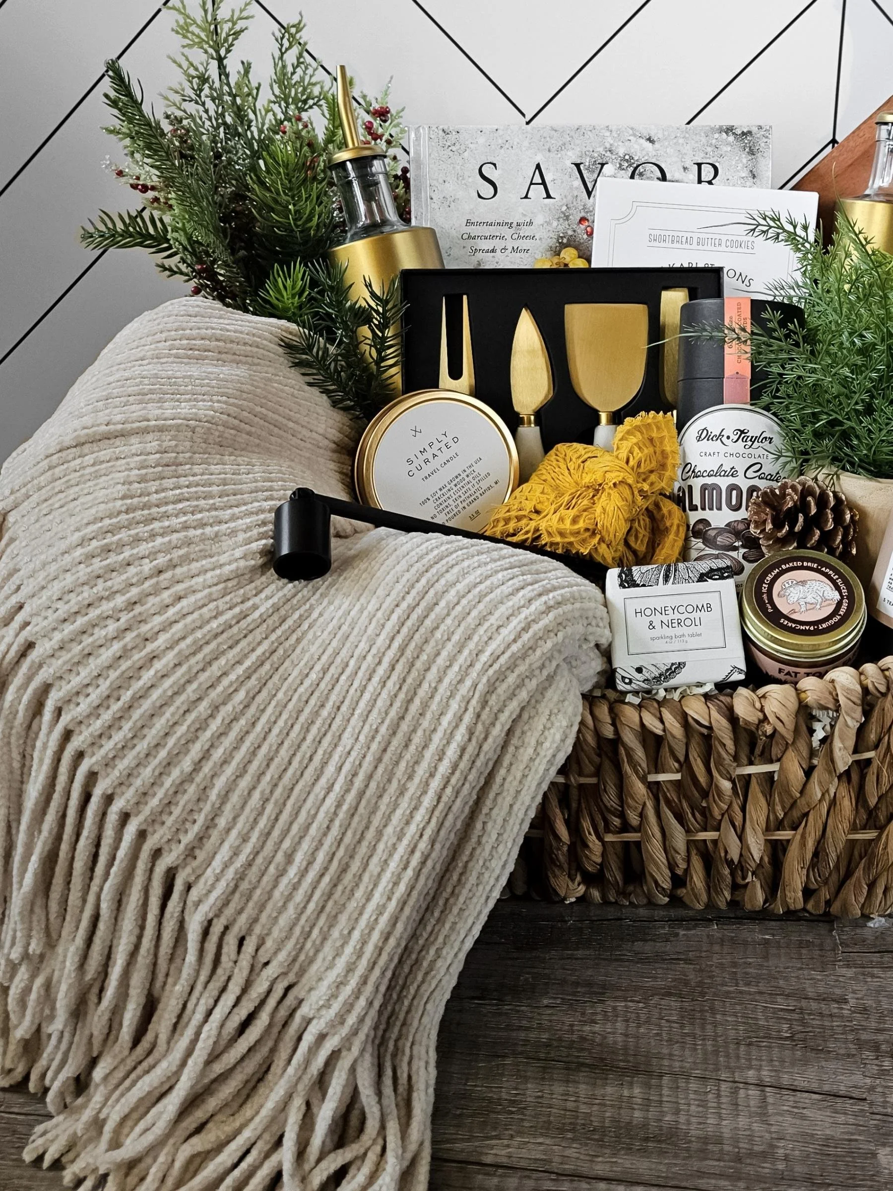 Curated neutral gift box including a plush throw, gourmet snacks, chai tea, bath tablet, candle, and beautifully crafted home essentials.