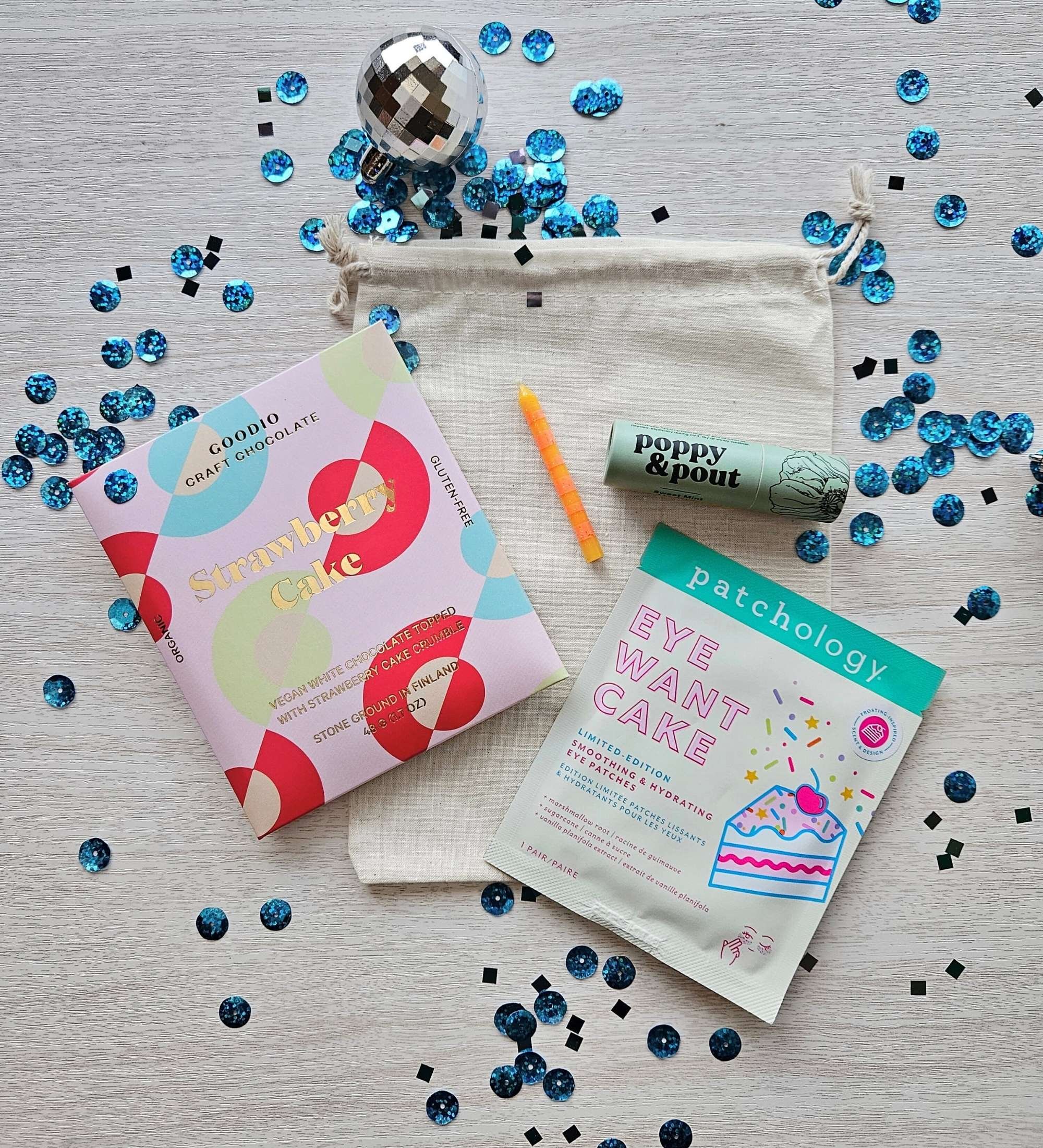 Affordable birthday gift set featuring a strawberry cake chocolate bar, Eat Cake eye gels, lip balm, and a colorful birthday candle.