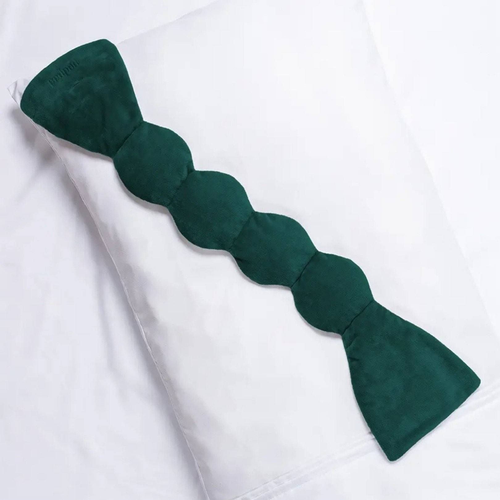 Dark emerald Nodpod weighted sleep mask, designed to provide deep-touch pressure and relieve headaches, promoting restful sleep.