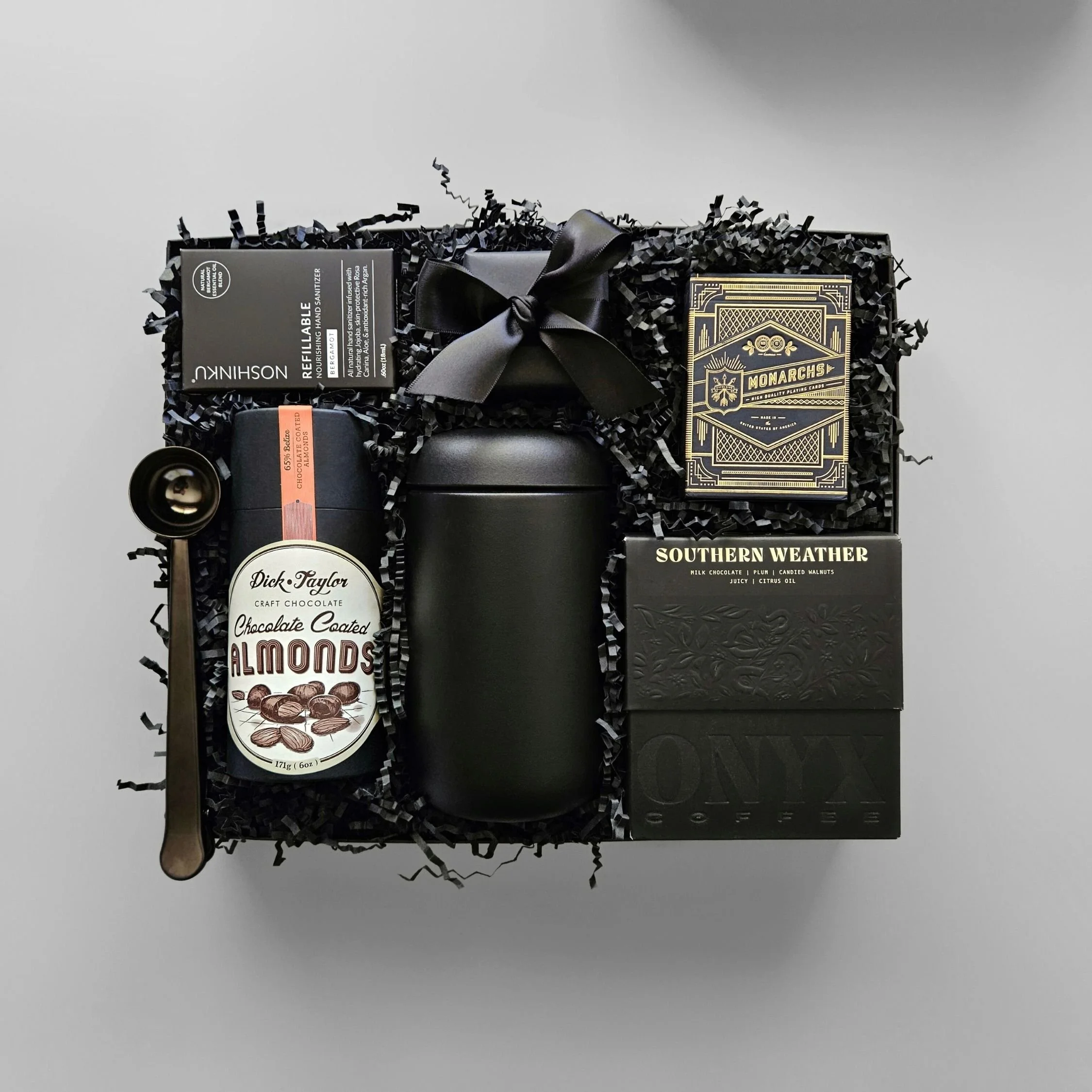 Sleek corporate gift box with gourmet coffee, chocolate almonds, premium playing cards, Fellow mug, coffee scoop, caramels, and bergamot hand sanitizer—styled for modern client gifting.