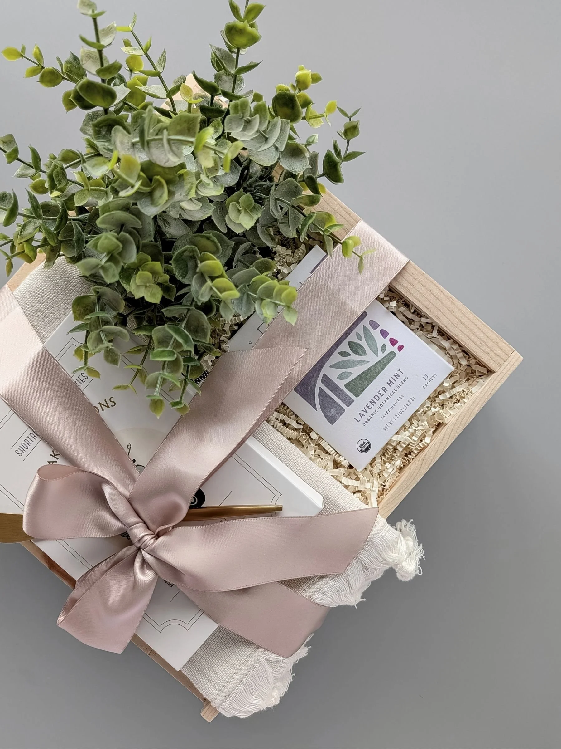 Curated Tea Time gift set featuring artisan tea, Turkish hand towel, lemon poppy cookies, and gold spreader in a wooden slide‑top box.