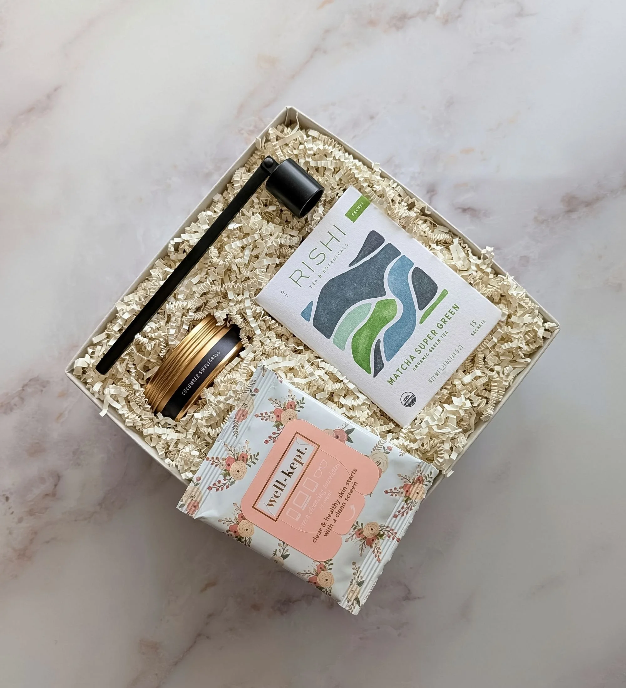 The Bloom gift box with matcha tea, cucumber sweet grass candle, floral screen wipes, and a black candle snuffer.