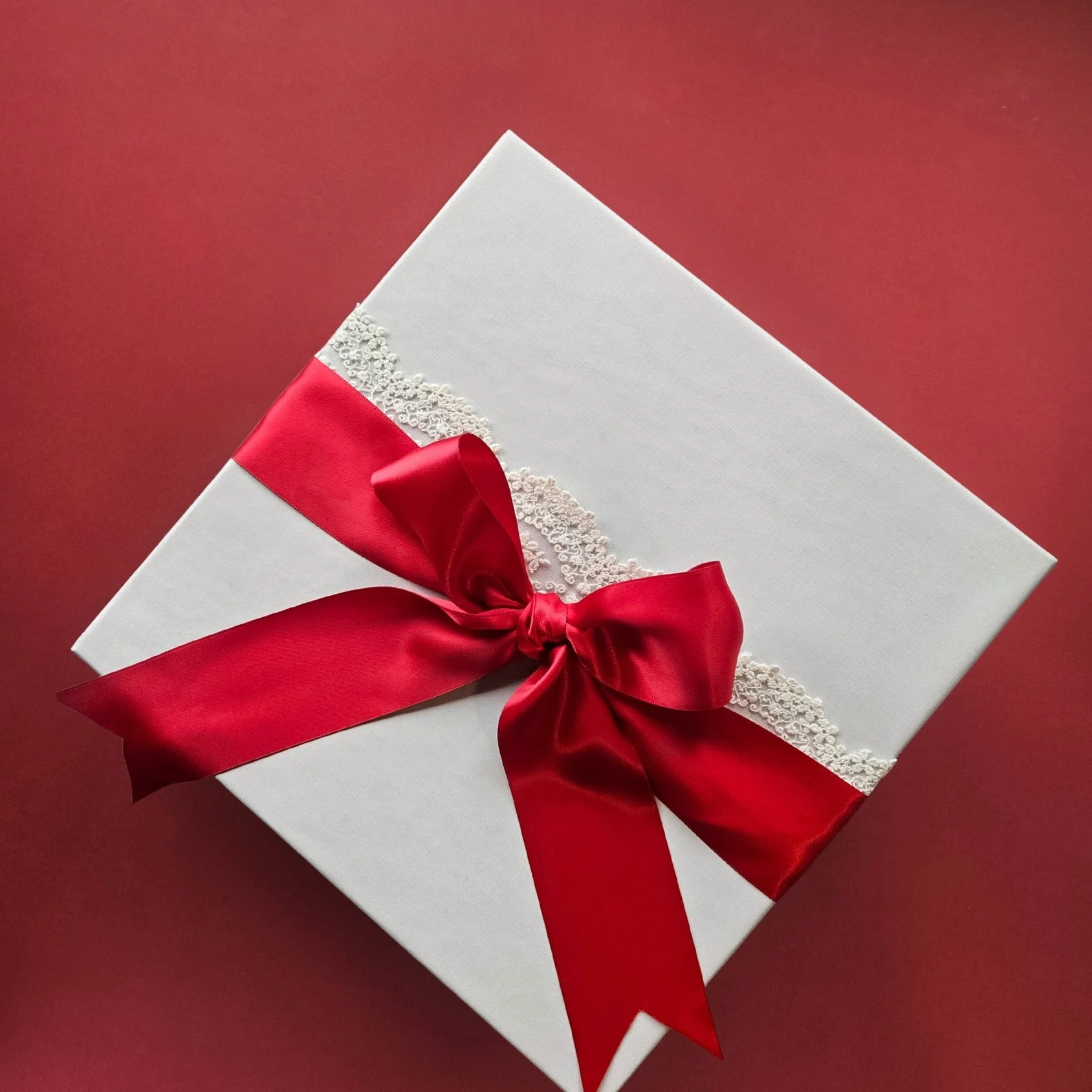Linen‑wrapped Love Letters gift box with lace ribbon and double red satin bow, styled for romantic and Valentine’s Day gifting.