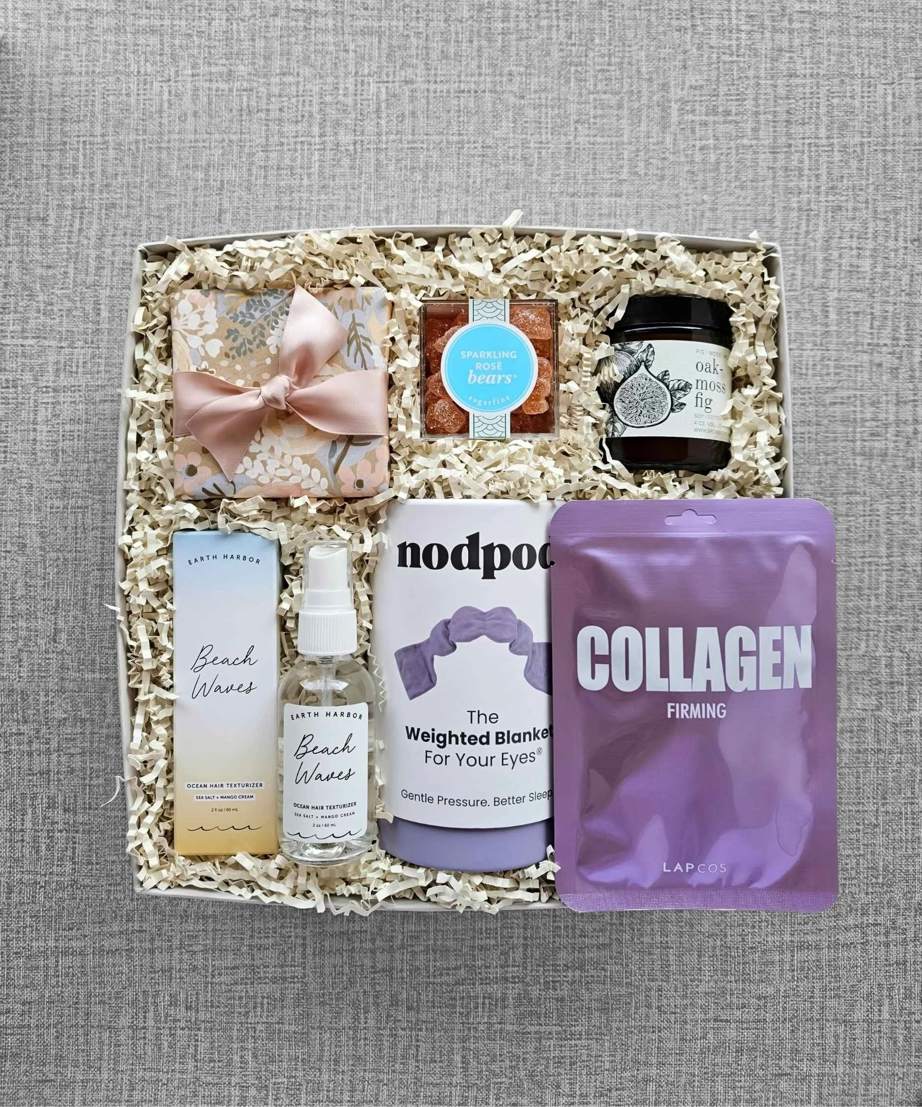 Self‑care gift box with weighted eye mask, face mask, eye gels, candle, and facial spray for relaxation.