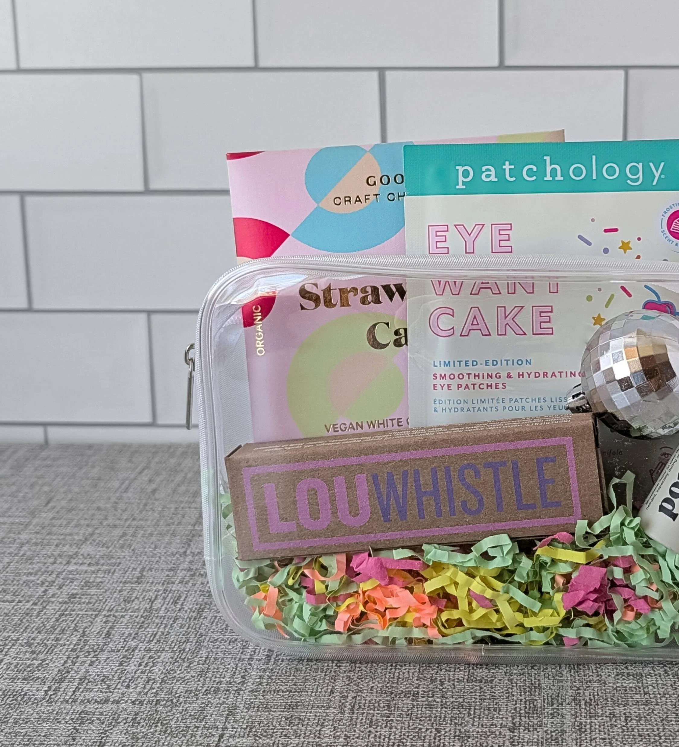 Bright and playful birthday gift set featuring eye gels, chocolate, lip balm, and a disco ball in a clear bag.