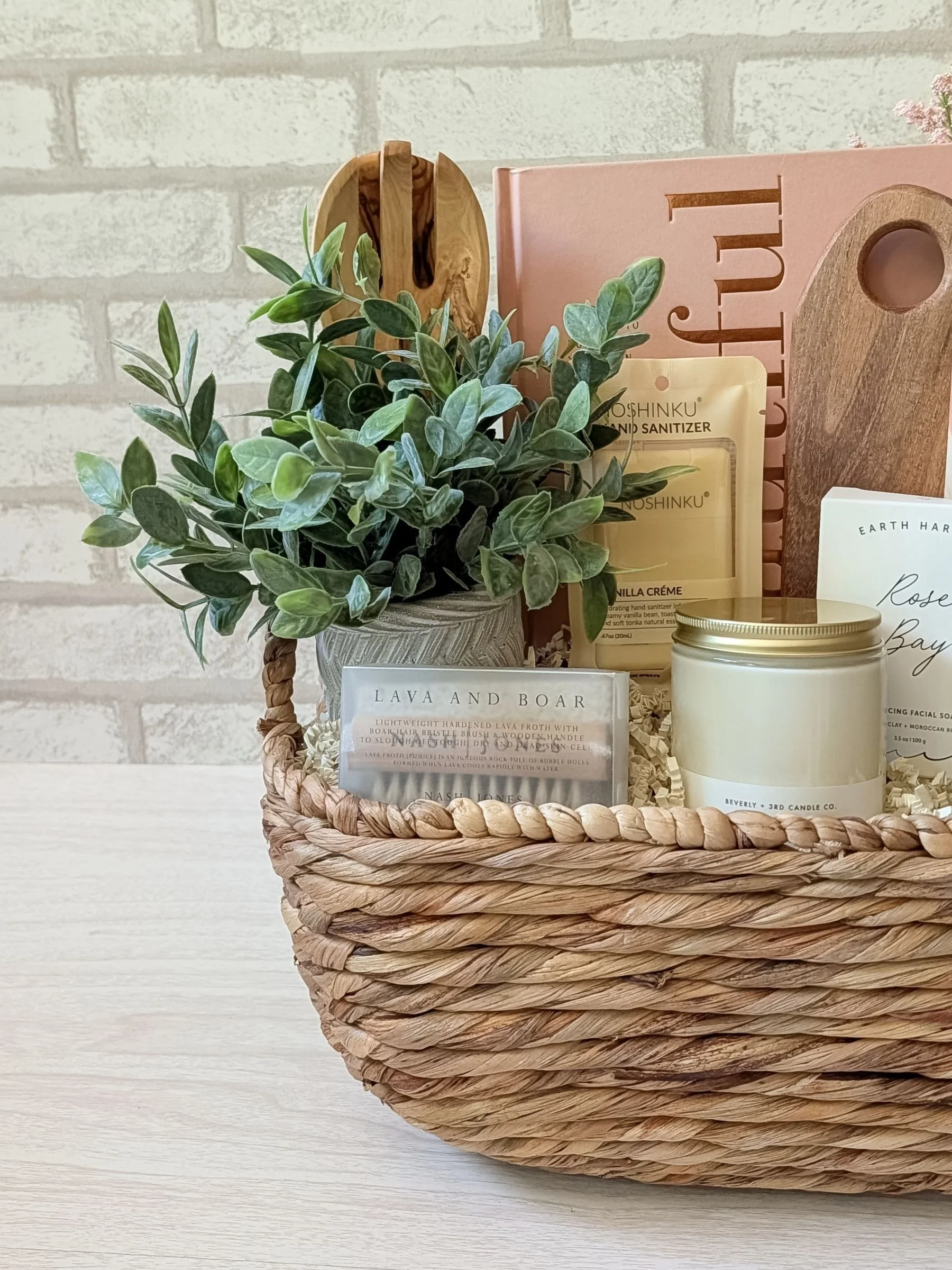 Luxury gift basket with vanilla crème hand sanitizer, boar and lava pumice brush, candle, wooden salad spoons, cookbook, and more.